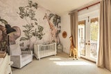 Das geschmackvoll eingerichtete Kinderzimmer wirkt dank des handgemalten Wandbilds bezaubernd. Ein entzückendes Detail ist die große Plüschgiraffe.