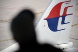 Ein Mann beobachtet ein Malaysia Airlines Flugzeug auf dem Rollfeld des internationalen Flughafens Kuala Lumpur.