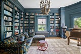 Traumplatz für Bücherfans: In die Bibliothek gelangt viel Tageslicht. Die blauen Bücherregale bieten reichlich Stauraum. Der Luster mit den Hirschköpfen ist ein extravaganter Eyecatcher.