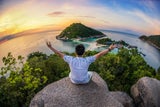 Mann sitzt auf einem Felsen in Thailand