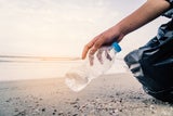 Beachcleaning Mann hebt Plastikflasche auf