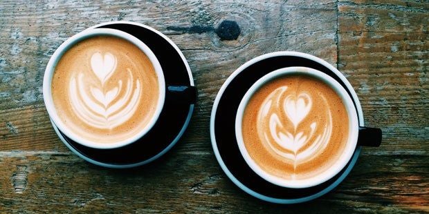 Zwei Kaffeetassen auf einem Holztisch.