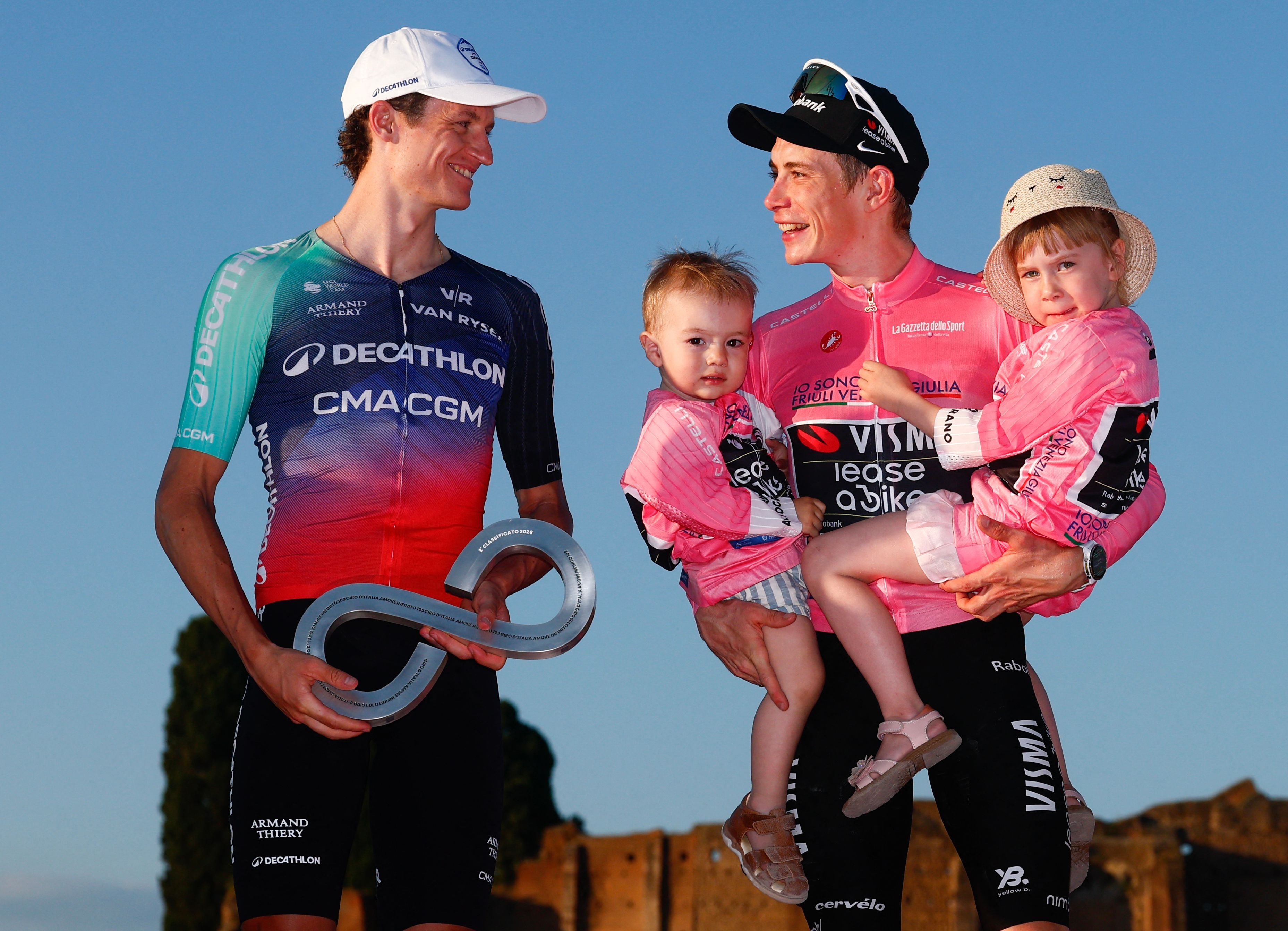 Team Visma Lease a Bike Danish rider Jonas Vingegaard C) wearing the overall leader's pink jersey and winner of the Giro d'Italia 2026 - Tour of Italy cycling race talks on the podium with second placed Decathlon CMA CGM Team Austrian rider Felix Gall, after the 21th and last stage in Rome, Italy, on May 31, 2026. (Photo by Luca Bettini / AFP)