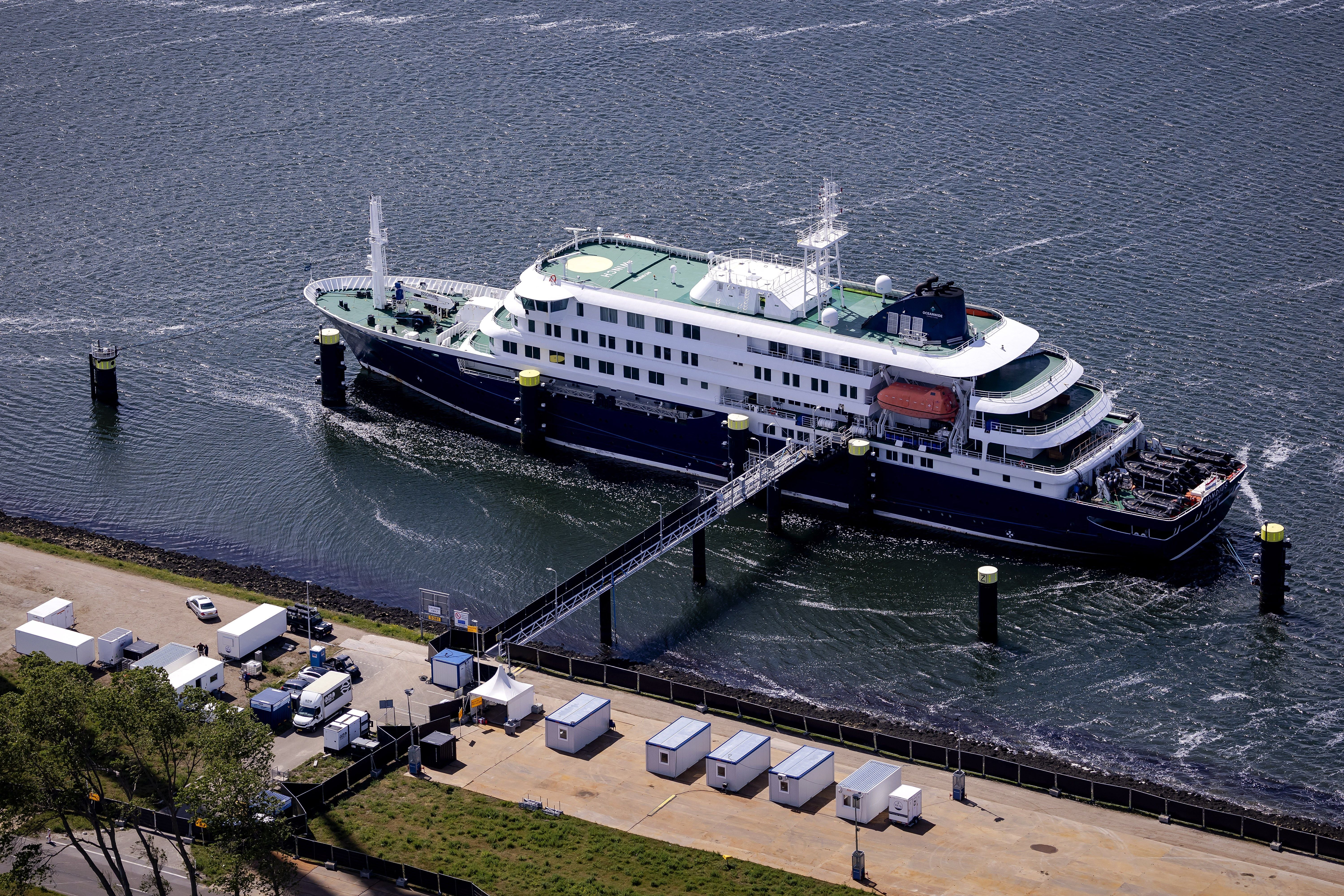 This aerial view shows the Dutch Hantavirus-hit cruise ship MV Hondius docked after arriving at the port of Rotterdam on May 18, 2026. A cruise ship that sparked global alarm after a deadly outbreak of hantavirus docked in Rotterdam harbour on May 18, with the skeleton crew facing weeks of quarantine. (Photo by Robin VAN LONKHUIJSEN / ANP / AFP) / Netherlands OUT / "The erroneous mention[s] appearing in the metadata of this photo by Peter LIPTON has been modified in AFP systems in the following manner: photographer byline [Robin van Lonkhuijsen instead of [Peter Lipton]. Please immediately remove the erroneous mention[s] from all your online services and delete it (them) from your servers. If you have been authorized by AFP to distribute it (them) to third parties, please ensure that the same actions are carried out by them. Failure to promptly comply with these instructions will entail liability on your part for any continued or post notification usage. Therefore we thank you very much for all your attention and prompt action. We are sorry for the inconvenience this notification may cause and remain at your disposal for any further information you may require."