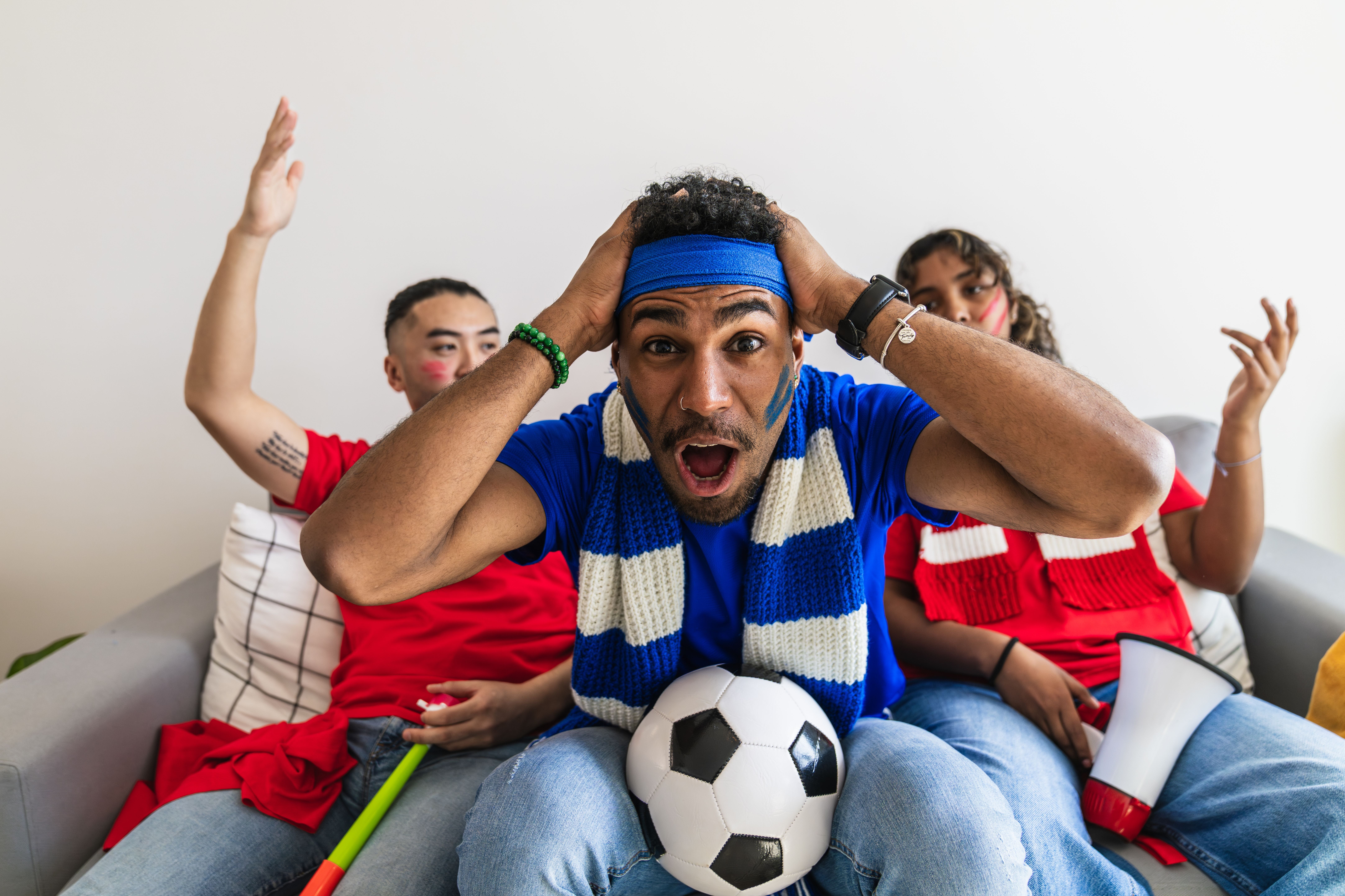 Group of multiethnic friends watching a soccer game at home, showing passionate reactions and emotional moments of excitement and disappointment