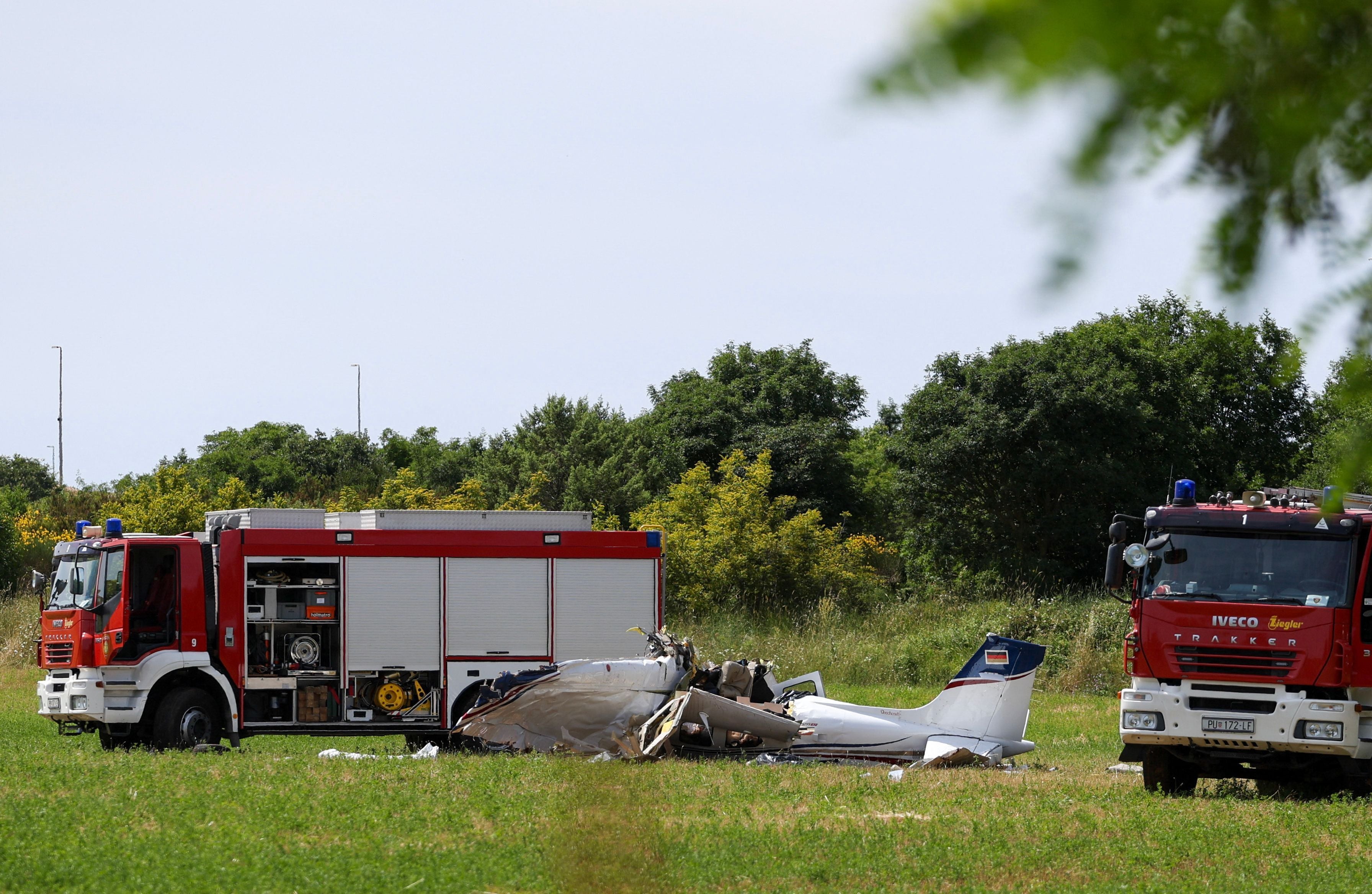 A police officer and firetrucks are seen at site of a small plane crash, which killed 4 people, in Medulin on Croatia's northern Adriatic coast, on June 4, 2026. The accident occurred in the Campanoz area, outside the town, and 'all emergency services are on the scene'. According to the state-run HRT broadcaster, it was a small aircraft registered in Germany, which had taken off from Austria with Medulin as its destination. (Photo by AFP)