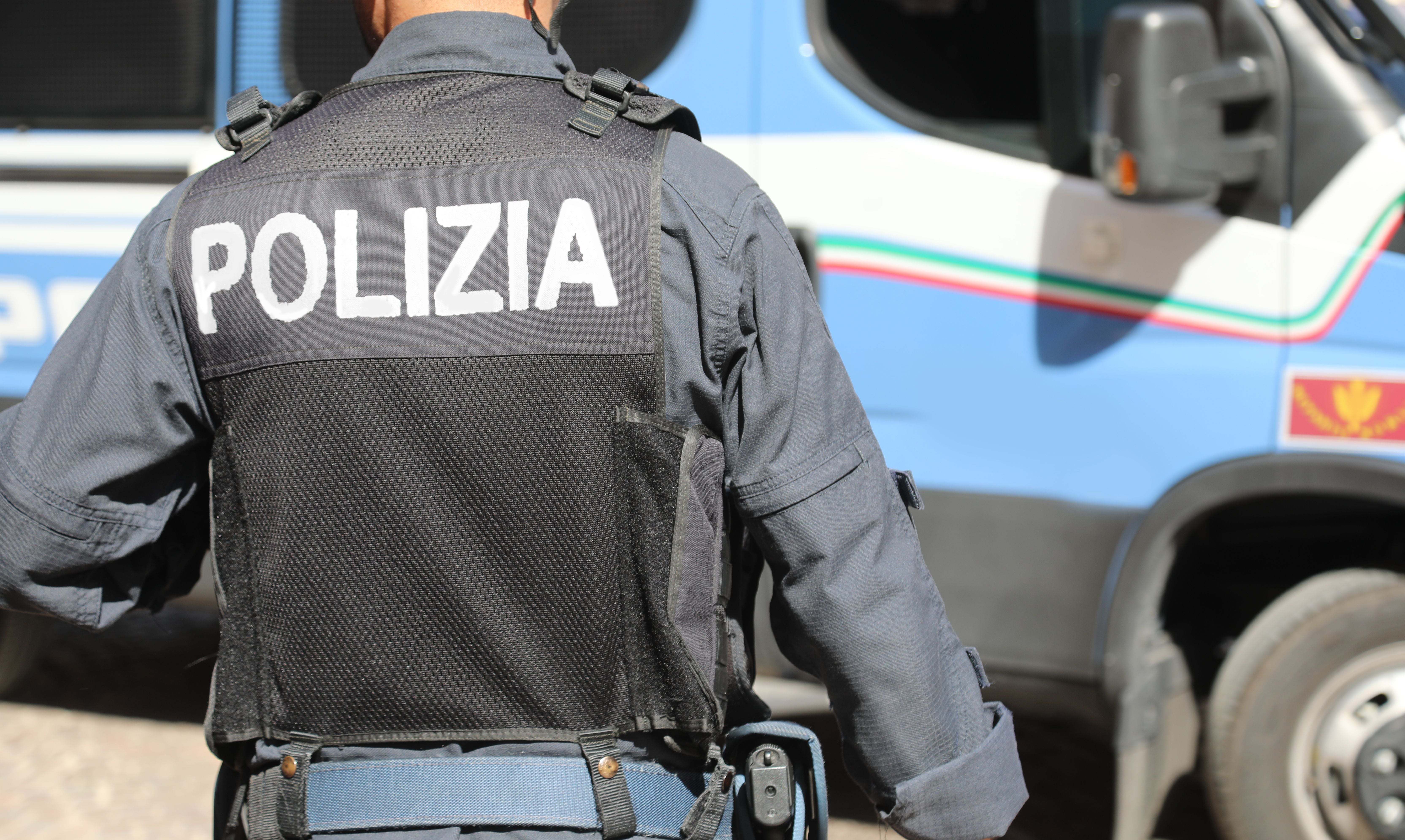 Vicenza, VI, Italy - May 10, 2024: Italian policeman in uniform with large POLIZIA text meaning POLICE in Italian and riot control van