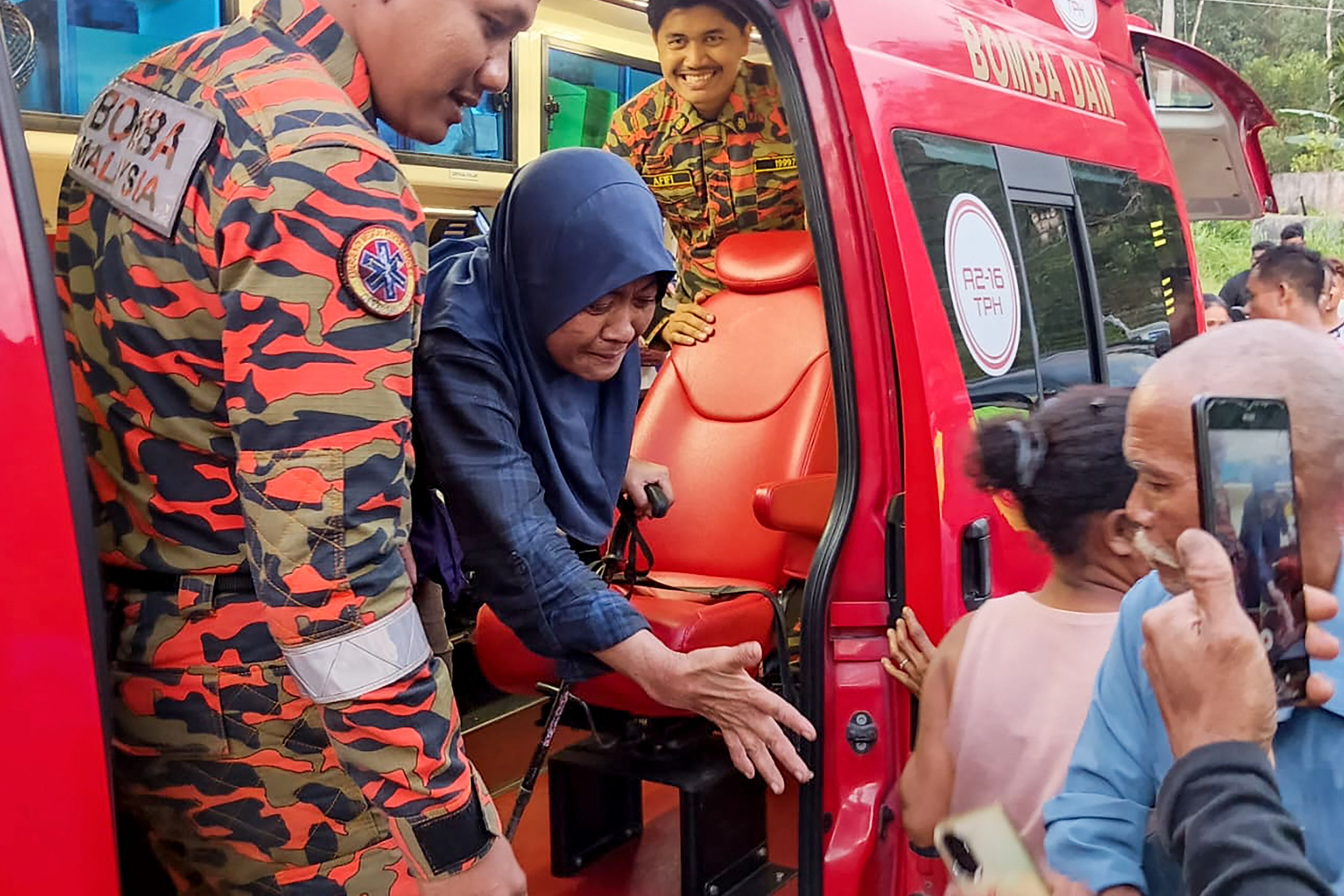 This handout photo taken and released by Perak's Fire and Rescue Department on June 6, 2026 shows rescuers assisting Jaslinda Saludin (2nd L) after she was found in a forested area in central Malaysia's Perak state. The rescue of a Malaysian hiker found alive after two weeks missing in the wilderness was hailed as 'a miracle' by a friend on June 7, 2026, as authorities ended a massive search that gripped the nation. (Photo by Handout / Perak's Fire and Rescue Department / AFP) / RESTRICTED TO EDITORIAL USE - MANDATORY CREDIT 'AFP PHOTO / Perak's Fire and Rescue Department' - HANDOUT - NO MARKETING NO ADVERTISING CAMPAIGNS - DISTRIBUTED AS A SERVICE TO CLIENTS