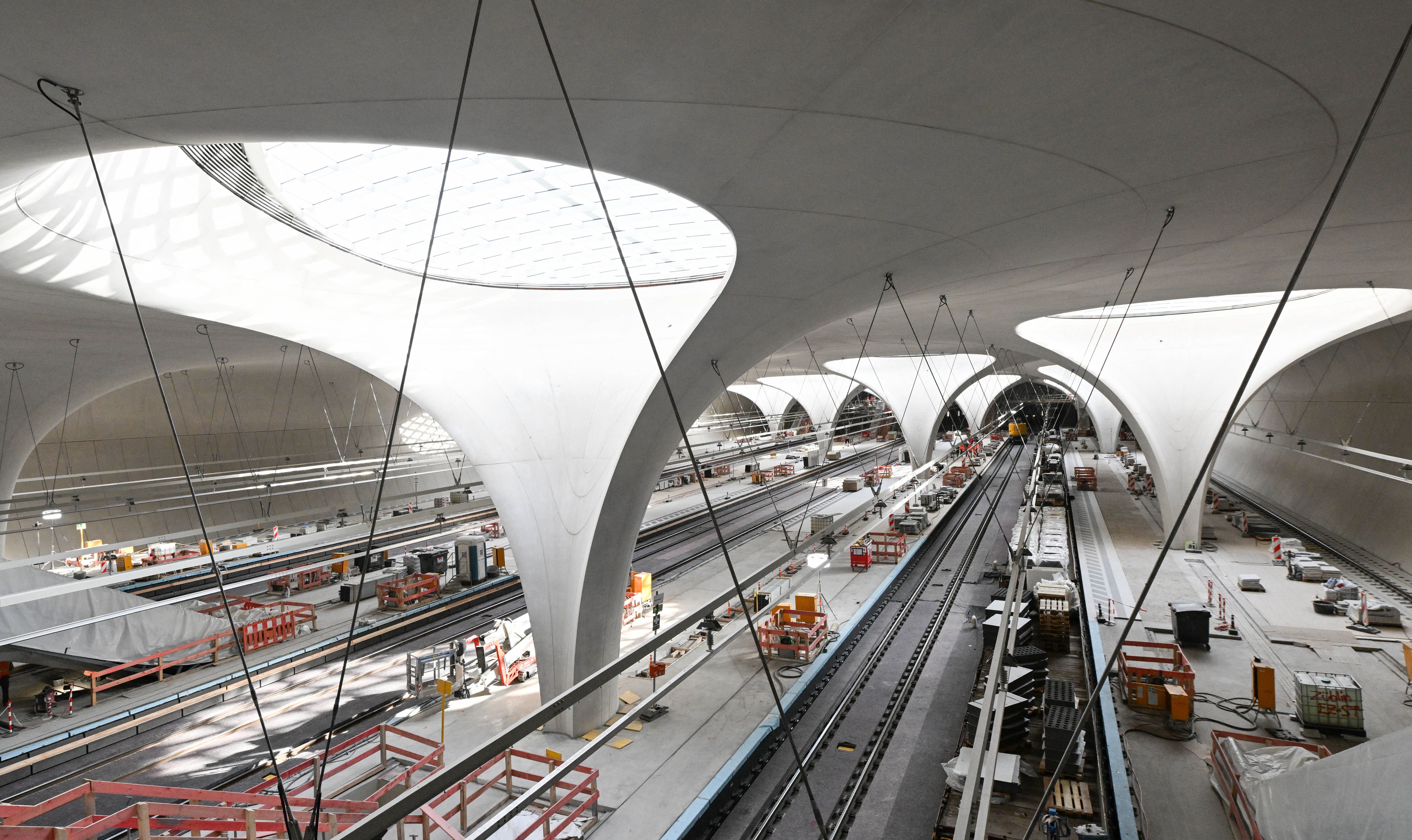 Pillars holding steel-glass skylights are pictured among tracks at the construction site of the new underground main station of railway development project Stuttgart 21 (S21) in Stuttgart, southern Germany, on November 20, 2025. The opening of a mammoth German rail project, which has become emblematic of the infrastructure woes plaguing Europe's biggest economy, has been delayed yet again, reports said November 19, 2025. 'Stuttgart 21' is envisaged as a futuristic rail hub in the southwestern city, but its inauguration has been repeatedly pushed back from an original date of 2019. Trains were due to finally start running from the new underground station in December 2026, before a full opening in the summer of 2027. (Photo by THOMAS KIENZLE / AFP)