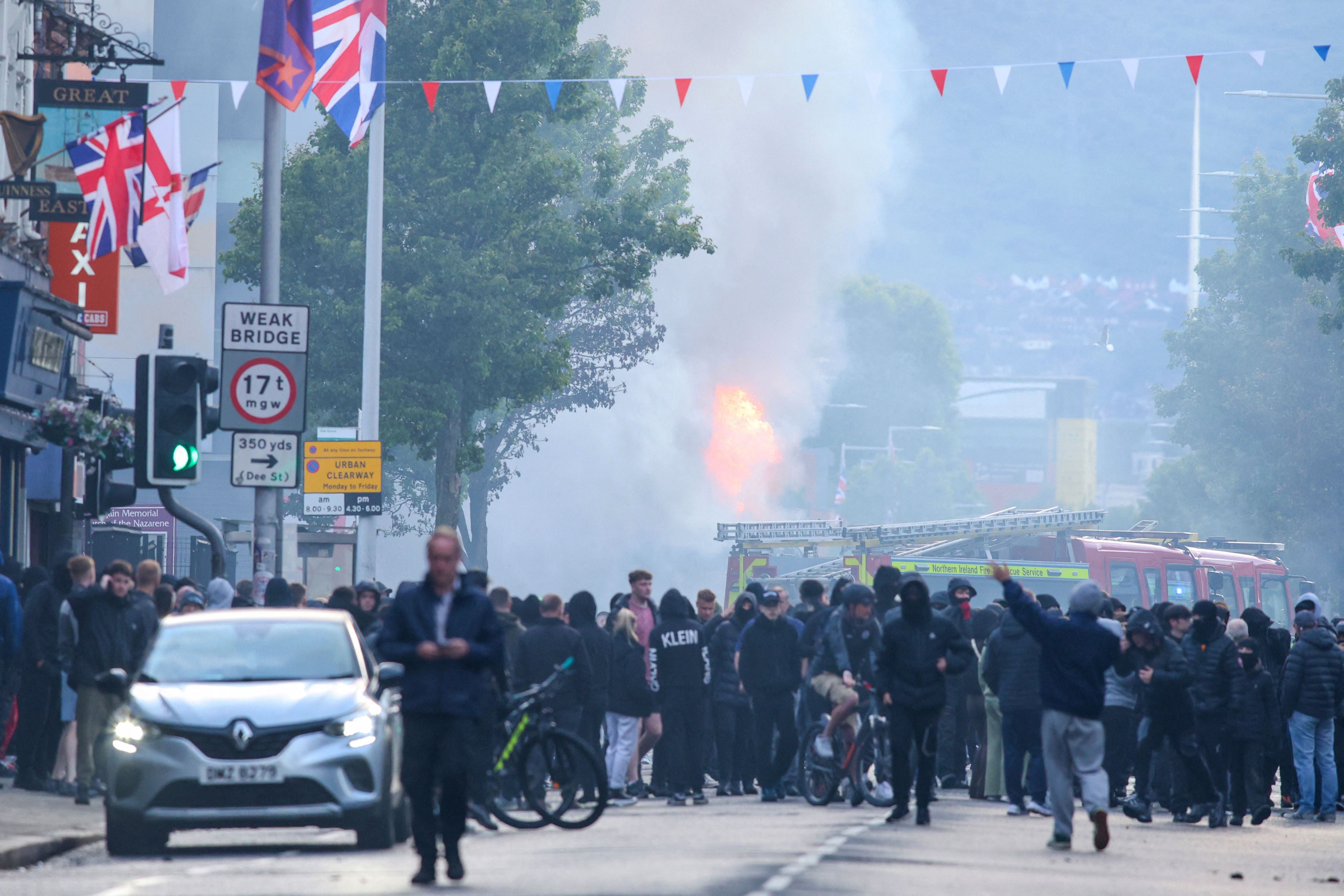 A burning bus is seen as protesters gather on the Newtownards road in east Belfast, Northern Ireland, in the evening of June 9, 2026. Northern Ireland police appealed for calm Tuesday after a stabbing in Belfast allegedly by a Sudanese suspect and captured in a graphic video prompted calls for anti-immigration protests from UK far-right figures. (Photo by Paul Faith / AFP)