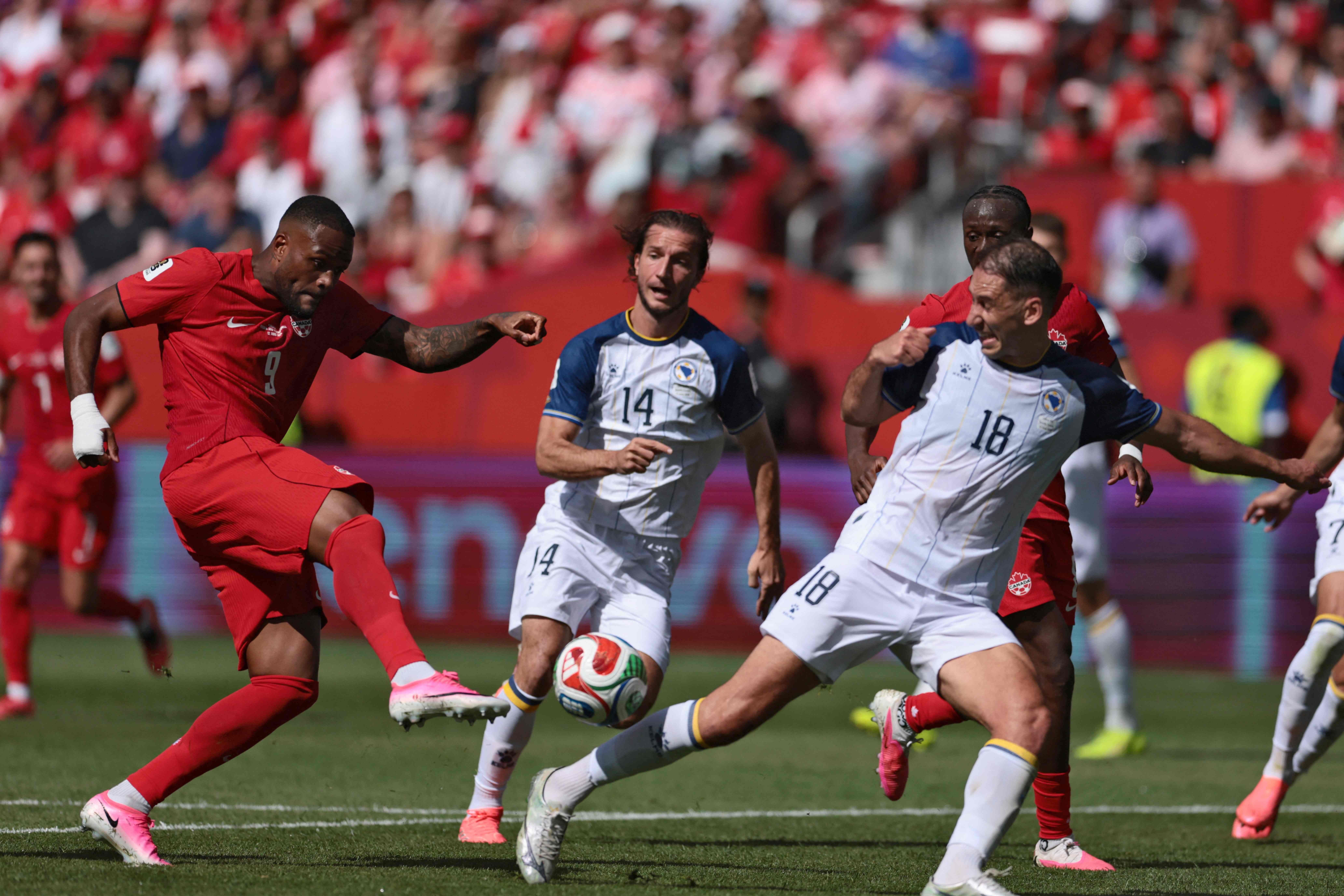 Canada's forward #09 Cyle Larin (L) scores the equalizer during the 2026 World Cup Group B football match between Canada and Bosnia and Herzegovina at the Toronto Stadium in Toronto on June 12, 2026. (Photo by Cole Burston / AFP)