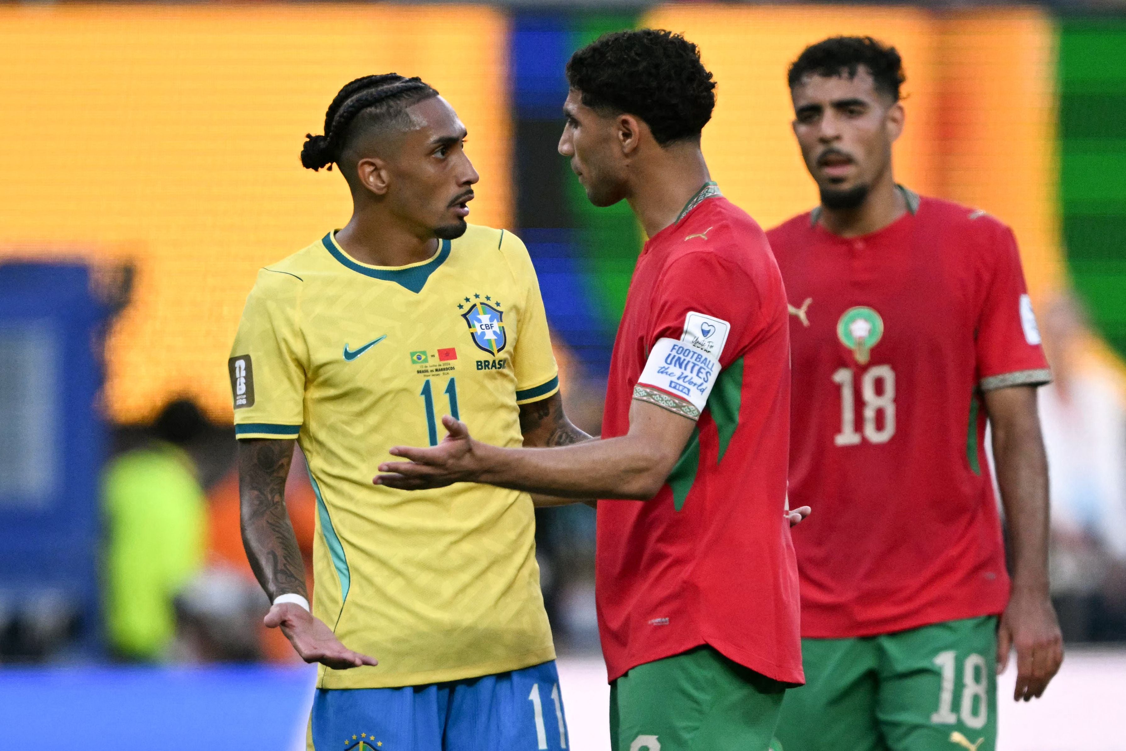 Brazil's forward #11 Raphinha (L) speaks with Morocco's defender #02 Achraf Hakimi during the 2026 World Cup Group C football match between Brazil and Morocco at the New York/New Jersey Stadium in East Rutherford on June 13, 2026. (Photo by Mauro PIMENTEL / AFP)