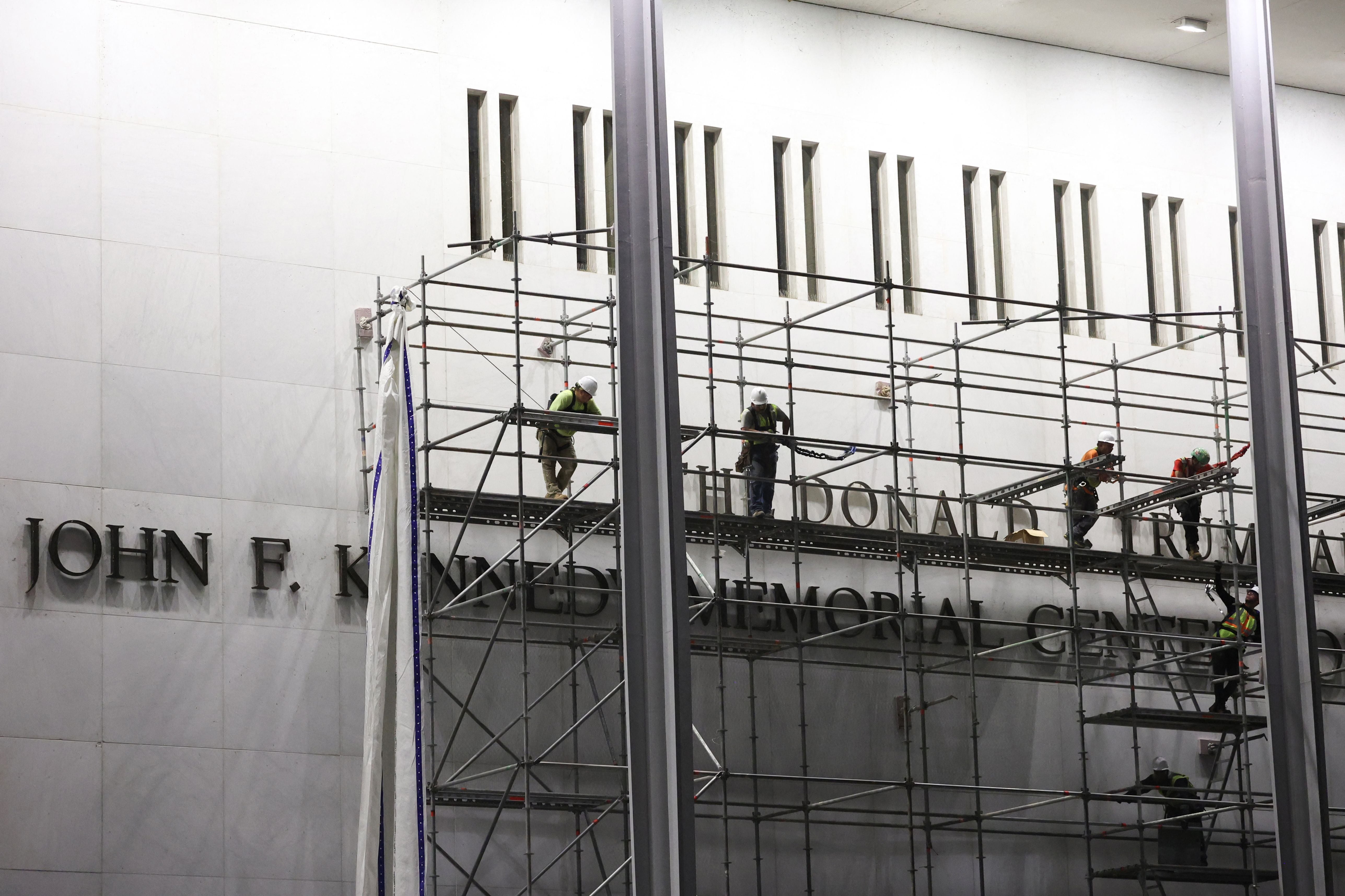 Workers build scaffolding near the signage for the 'Donald J. Trump and John F. Kennedy Memorial Center for the Performing Arts' in Washington, DC, early on June 13, 2026. A US federal judge on June 12 rejected a bid by the board of the Kennedy Center and the Justice Department to halt the removal of President Donald Trump's name from the performing arts venue. District Judge Christopher Cooper, in a ruling last month, ordered Trump's name taken off the iconic building in the nation's capital by Friday, June 12, 2026. (Photo by Alex WROBLEWSKI / AFP)