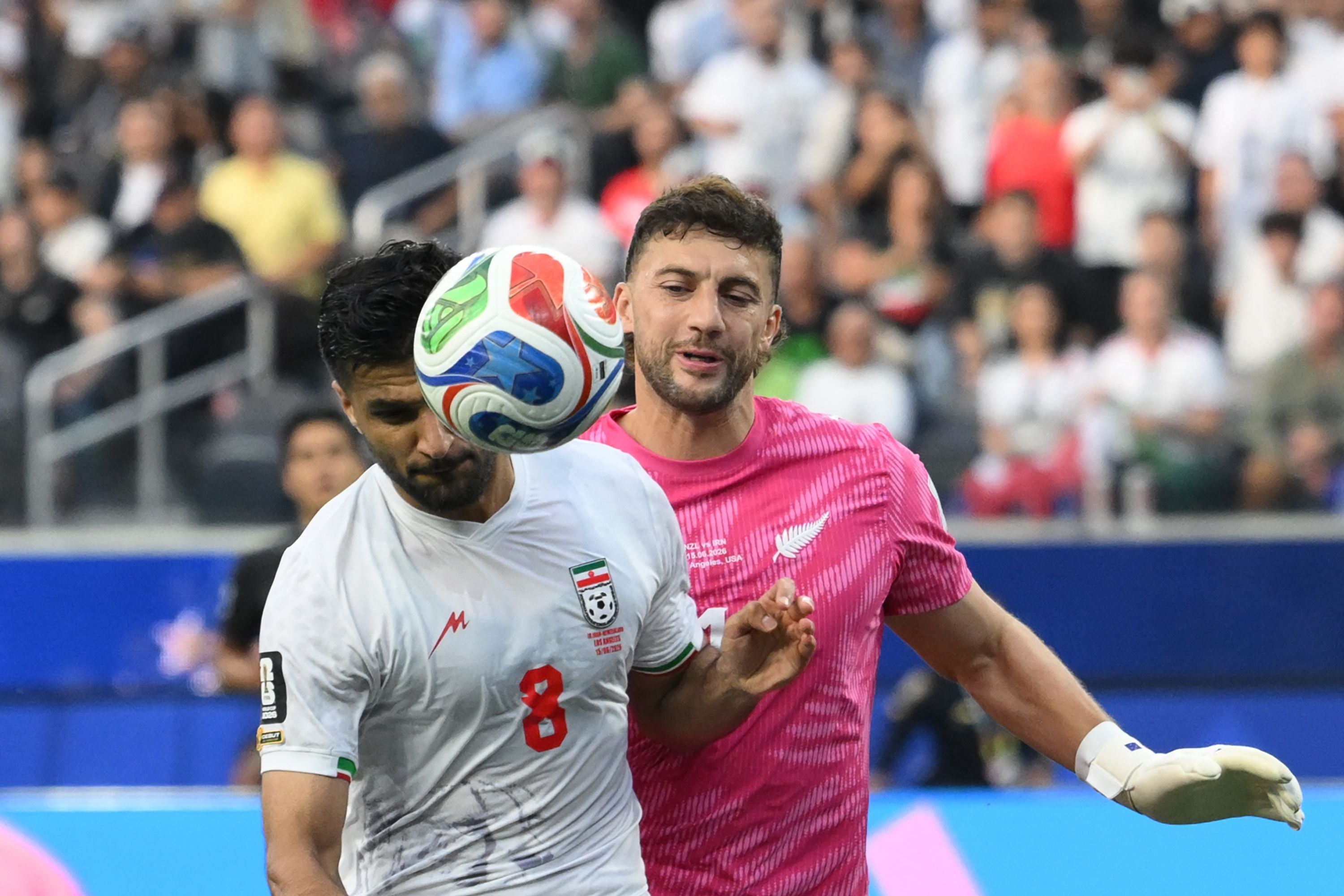 Iran's midfielder #08 Mohammad Mohebbi and New Zealand's goalkeeper #01 Max Crocombe fight for the ball during the 2026 World Cup Group G football match between Iran and New Zealand at Los Angeles Stadium in Inglewood on June 15, 2026. (Photo by Patrick T. Fallon / AFP)