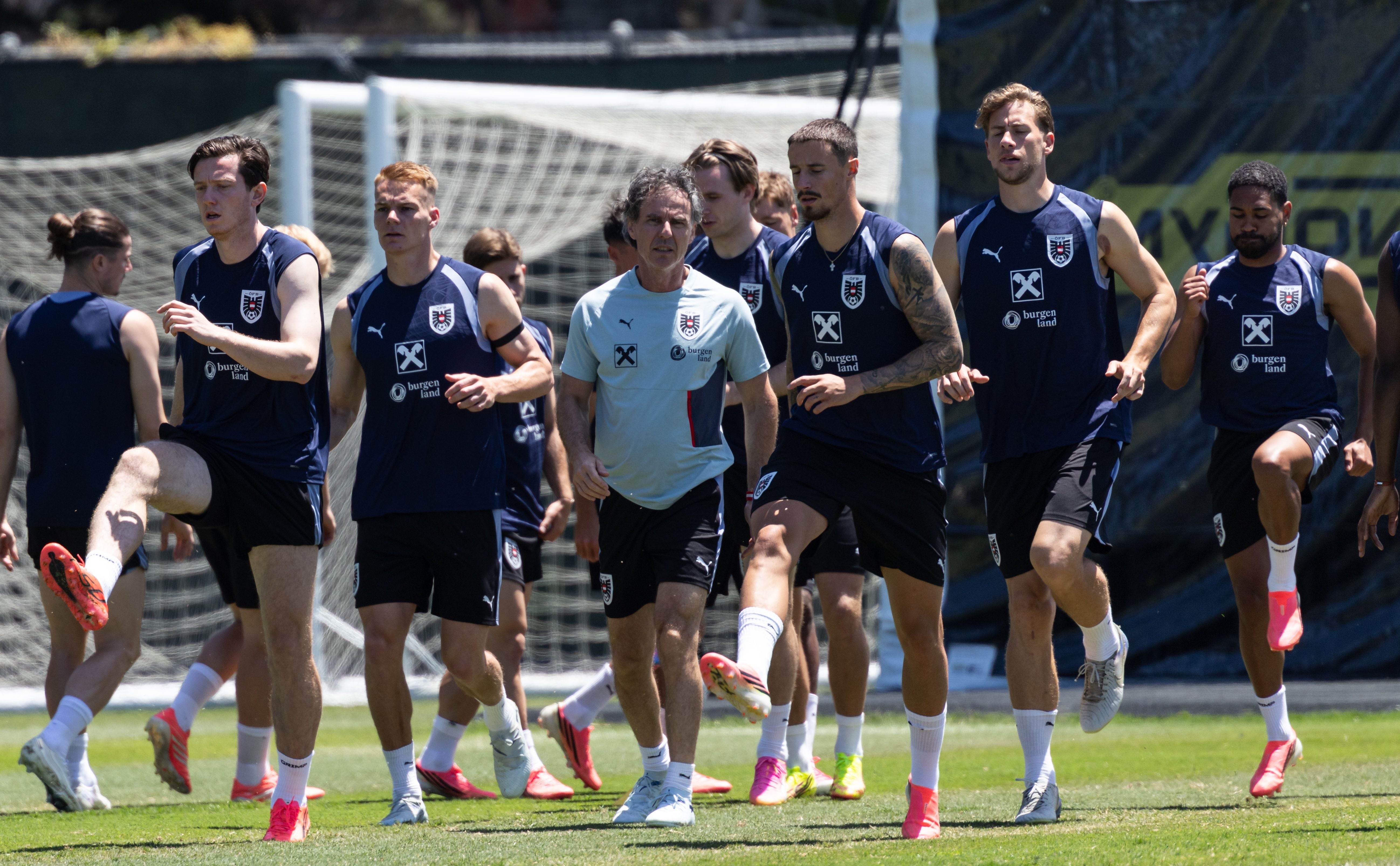 ÖFB-Teamchef Ralf Rangnick läuft im hellgrauen Trainingsshirt gemeinsam mit österreichischen Nationalspielern wie Michael Gregoritsch, Philipp Lienhart und Phillipp Mwene beim Aufwärmen auf einem Rasenplatz.