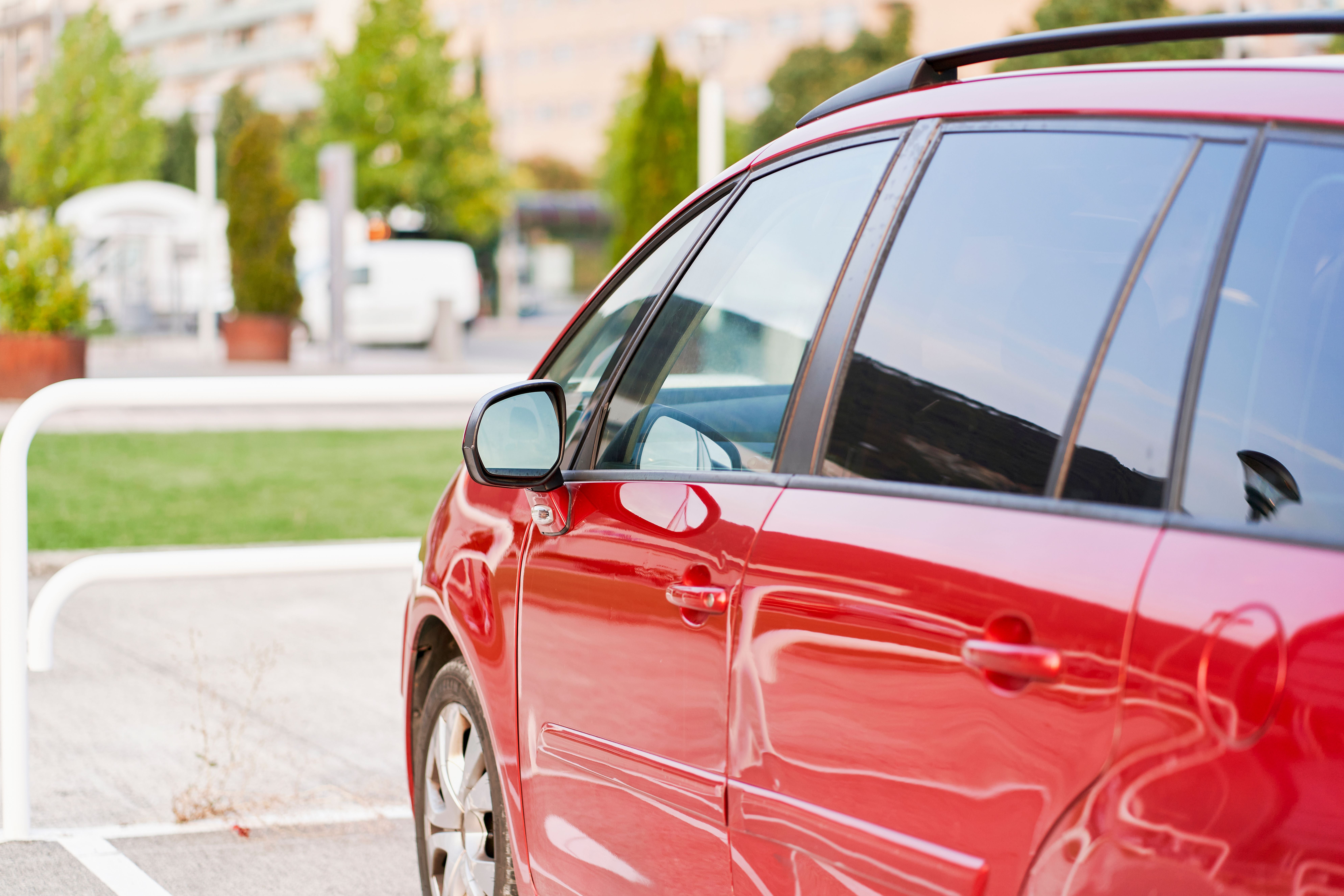 side view of the exterior of a red car parked without people with its doors and windows closed