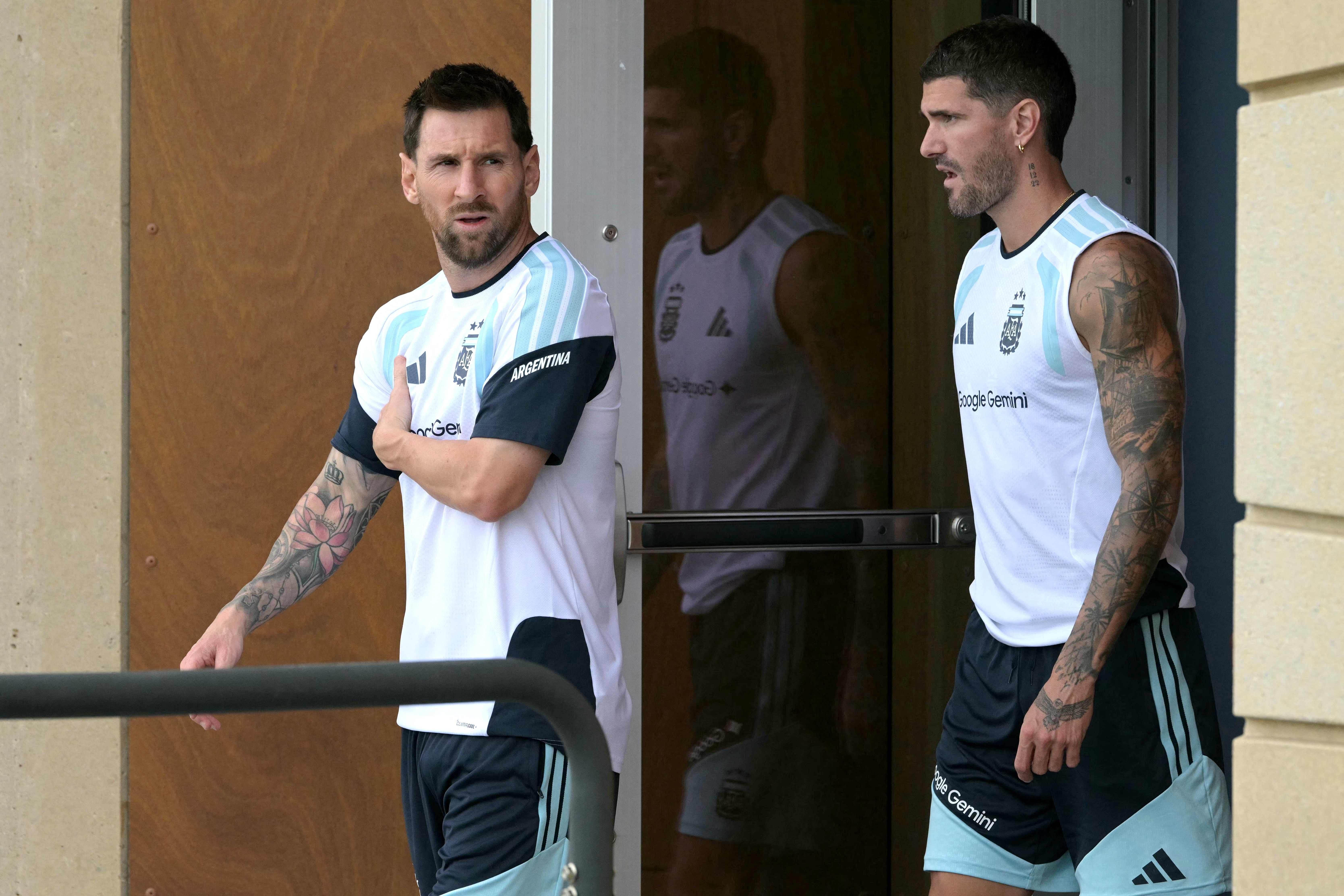 Zwei argentinische Fußballspieler betreten gemeinsam ein Trainingsgebäude in Sportkleidung.