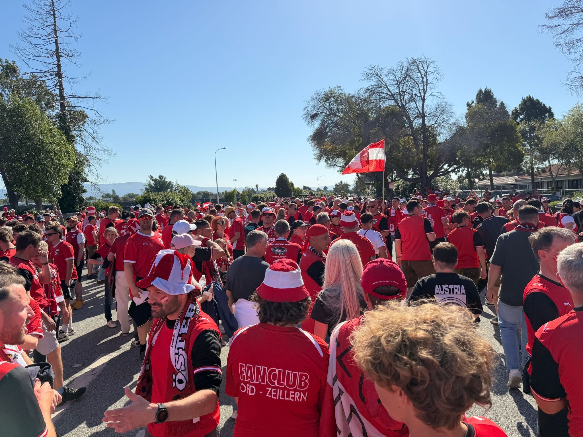 Viele Menschen in roten Österreich-Trikots marschieren beim ÖFB-Fanmarsch auf einer Straße.
