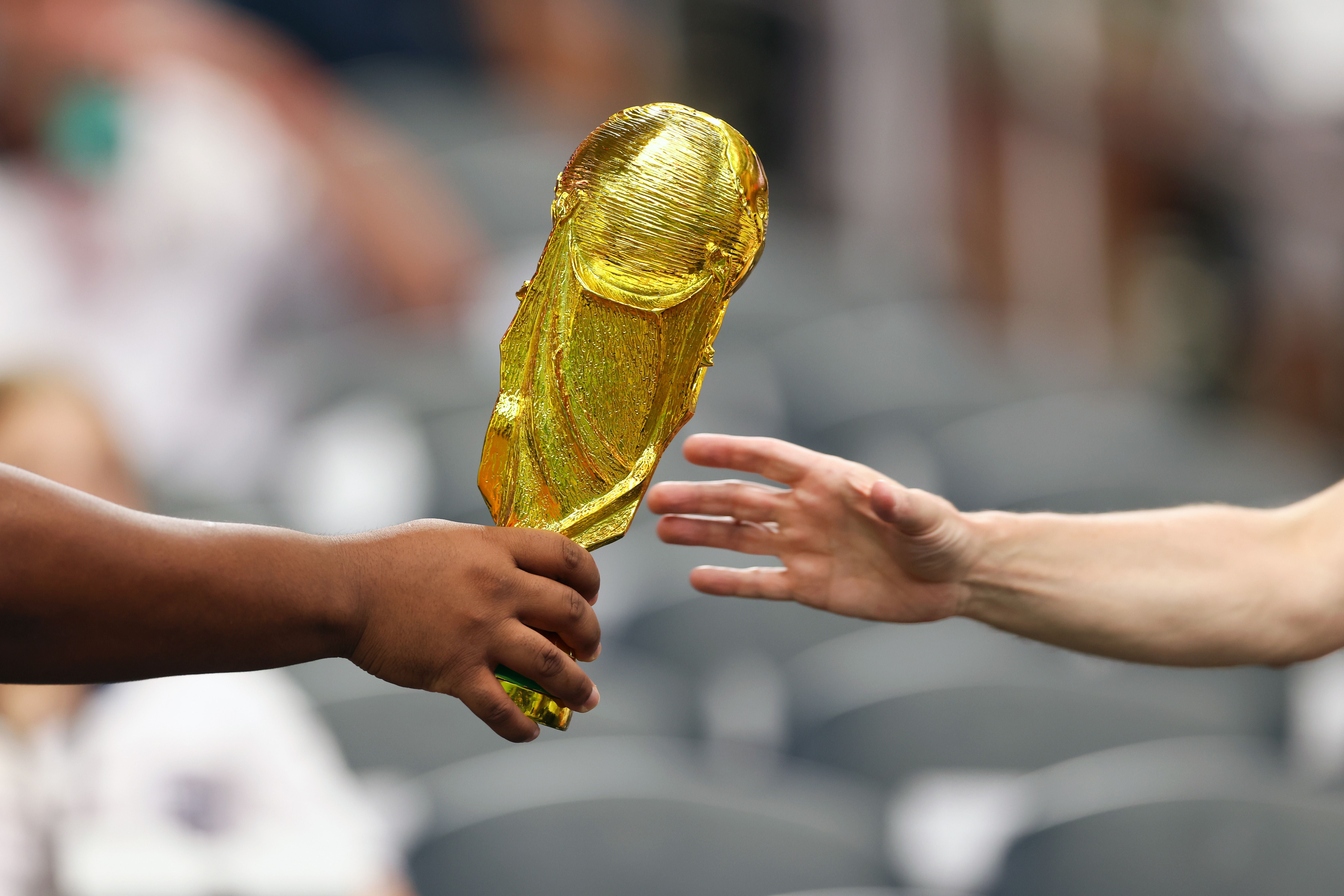 DALLAS, TEXAS - JUNE 17: A fan hands replica World Cup trophy is handed to another fan during the FIFA World Cup 2026 Group L match between England and Croatia at Dallas Stadium on June 17, 2026 in Dallas, Texas. (Photo by Catherine Ivill - AMA/Getty Images)