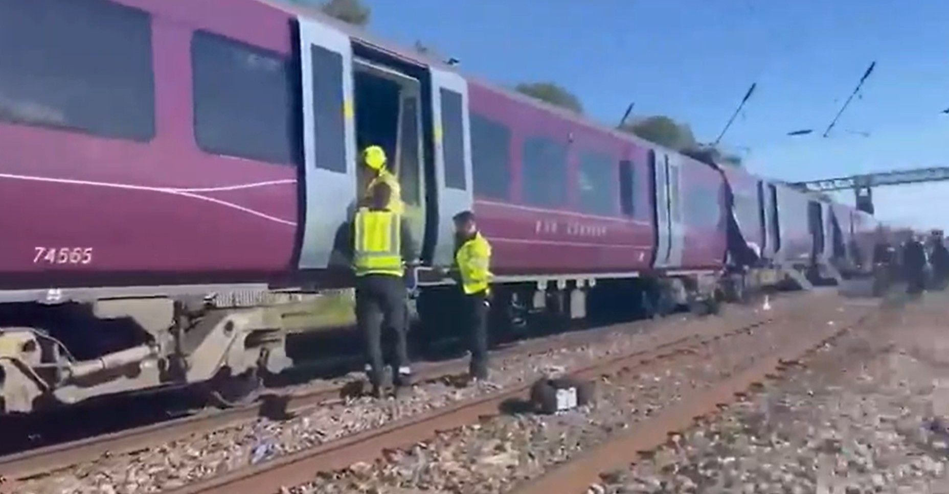 Drei Einsatzkräfte stehen an einem Unfall-Zug in England.
