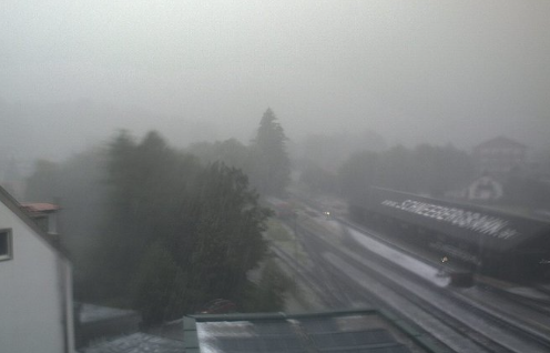 Bahnhof und Schienen bei starkem Unwetter und eingeschränkter Sicht durch Regen.