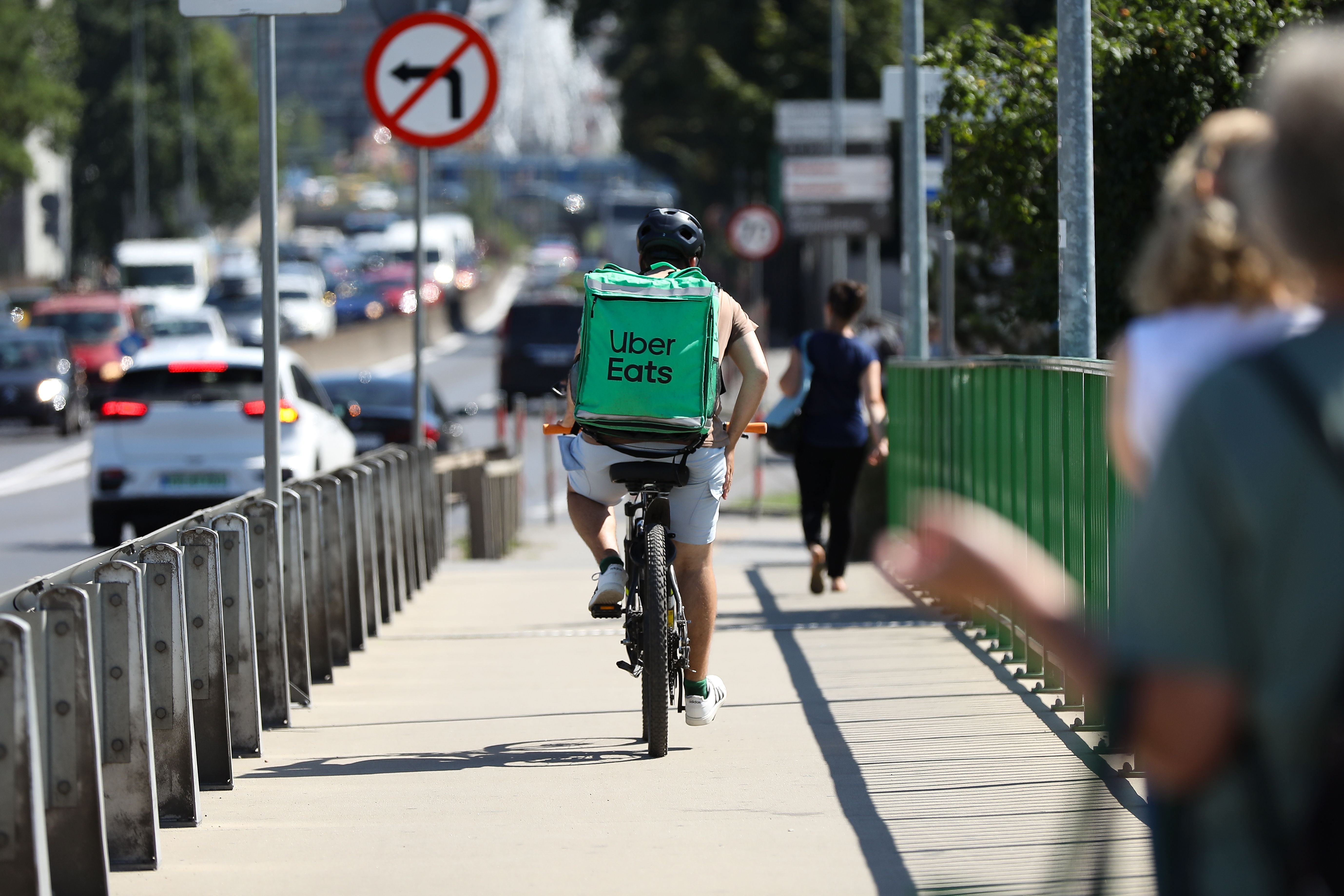 Ein Uber Eats-Kurier fährt mit dem Fahrrad auf einem Bürgersteig in der Stadt.