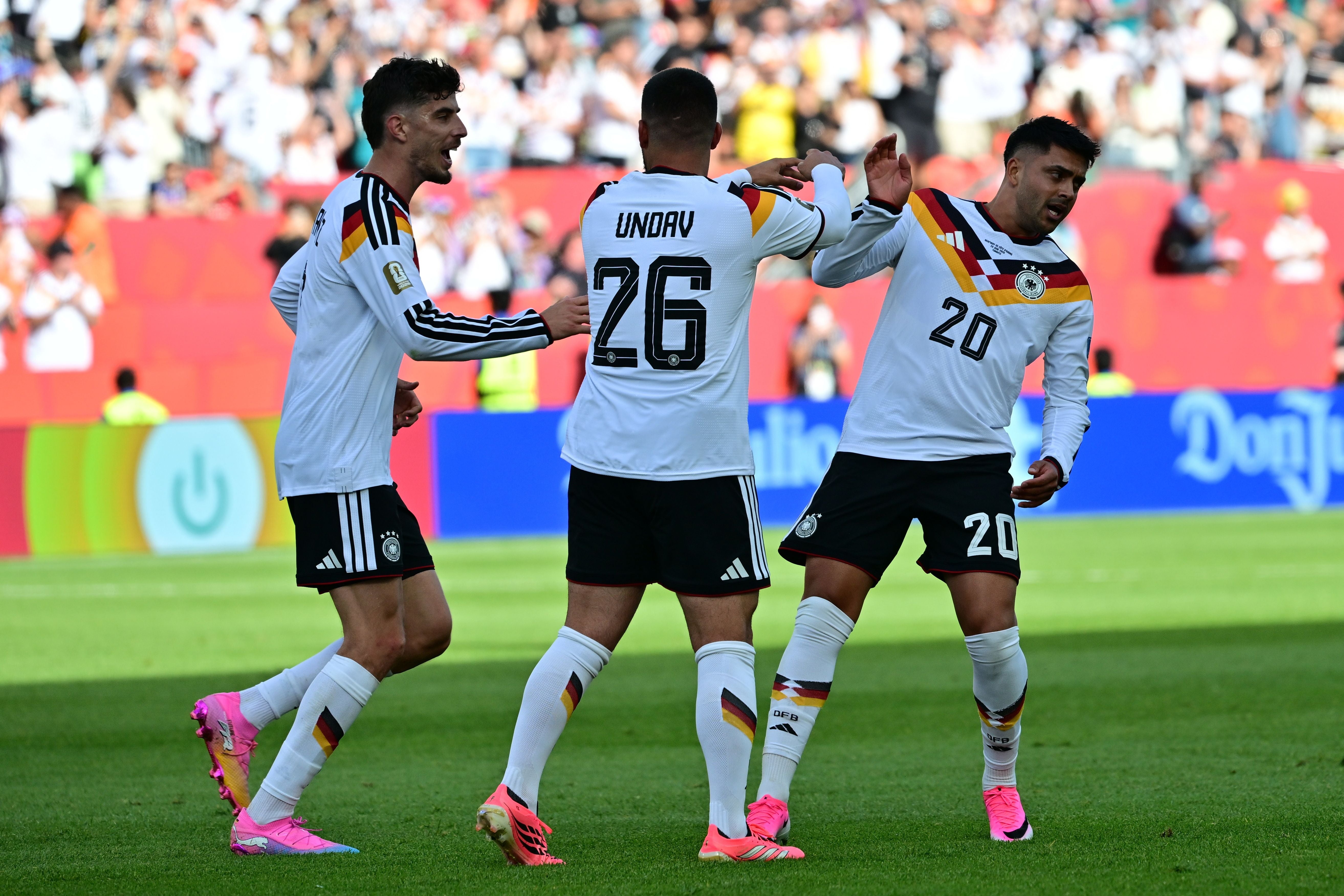 Drei deutsche Fußballspieler jubeln zusammen auf dem Spielfeld bei einem WM-Spiel.