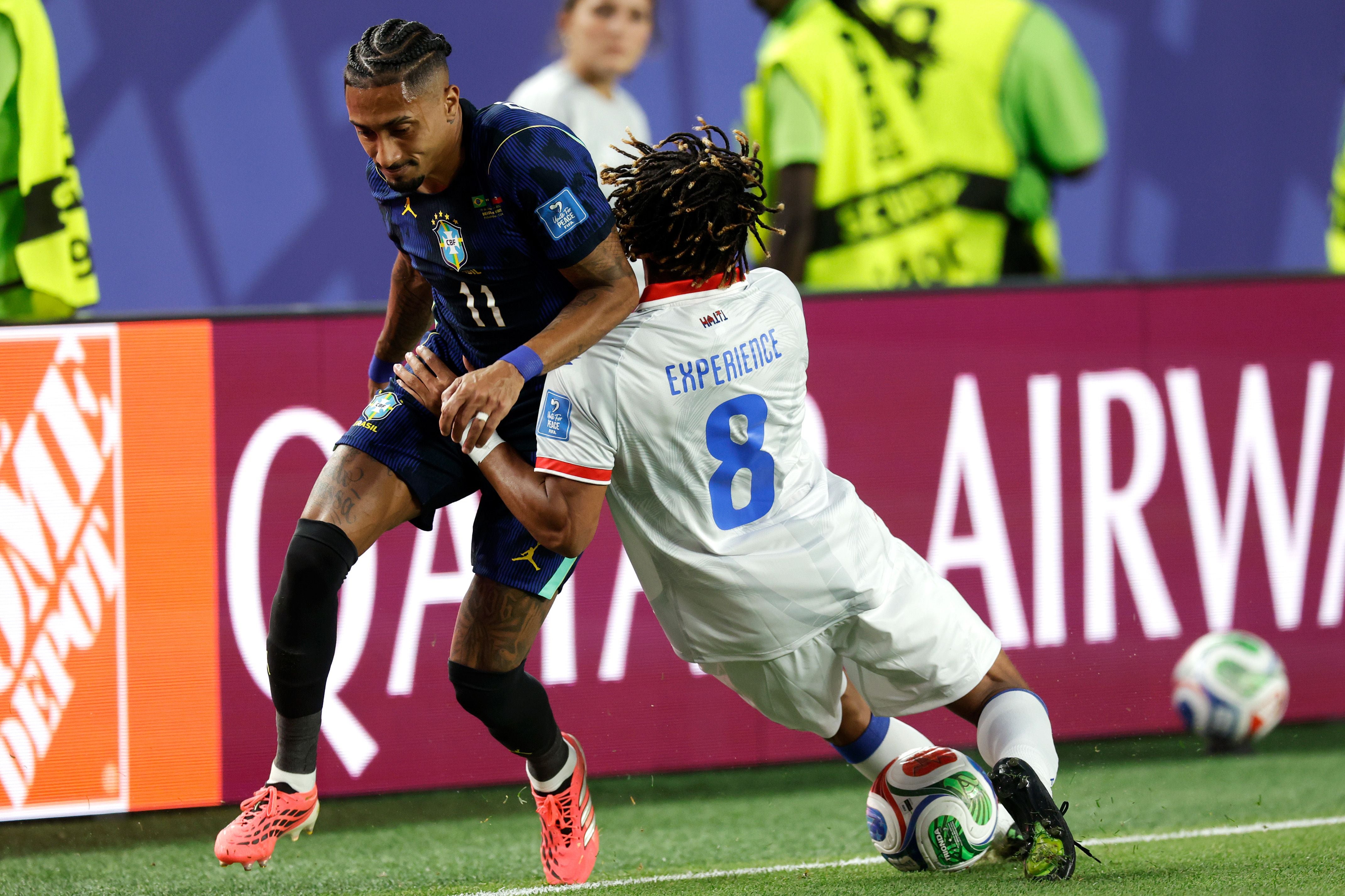 Ein brasilianischer und ein haitianischer Fußballspieler kämpfen um den Ball am Spielfeldrand.