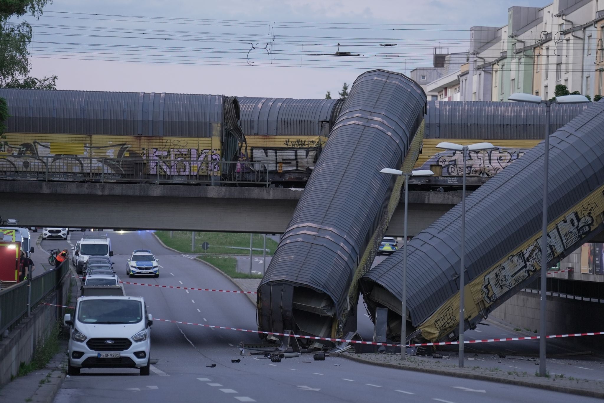 Die zwei entgleisten Güterzugwaggons liegen von einer Brücke gestürzt auf einer gesperrten Straße.