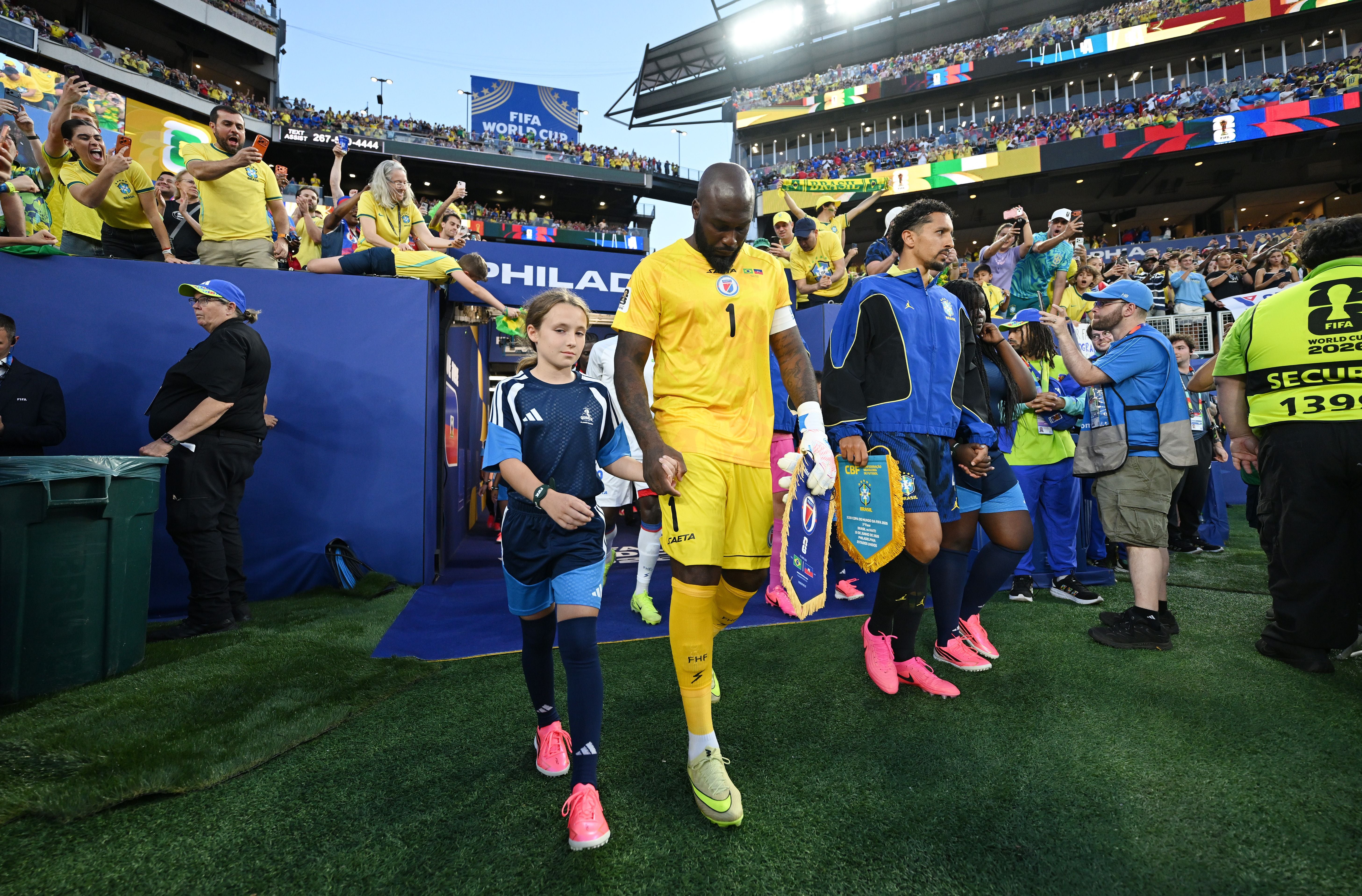 Spieler laufen mit Kindern ins Stadion ein, Fans jubeln beim FIFA WM-Spiel in Philadelphia.