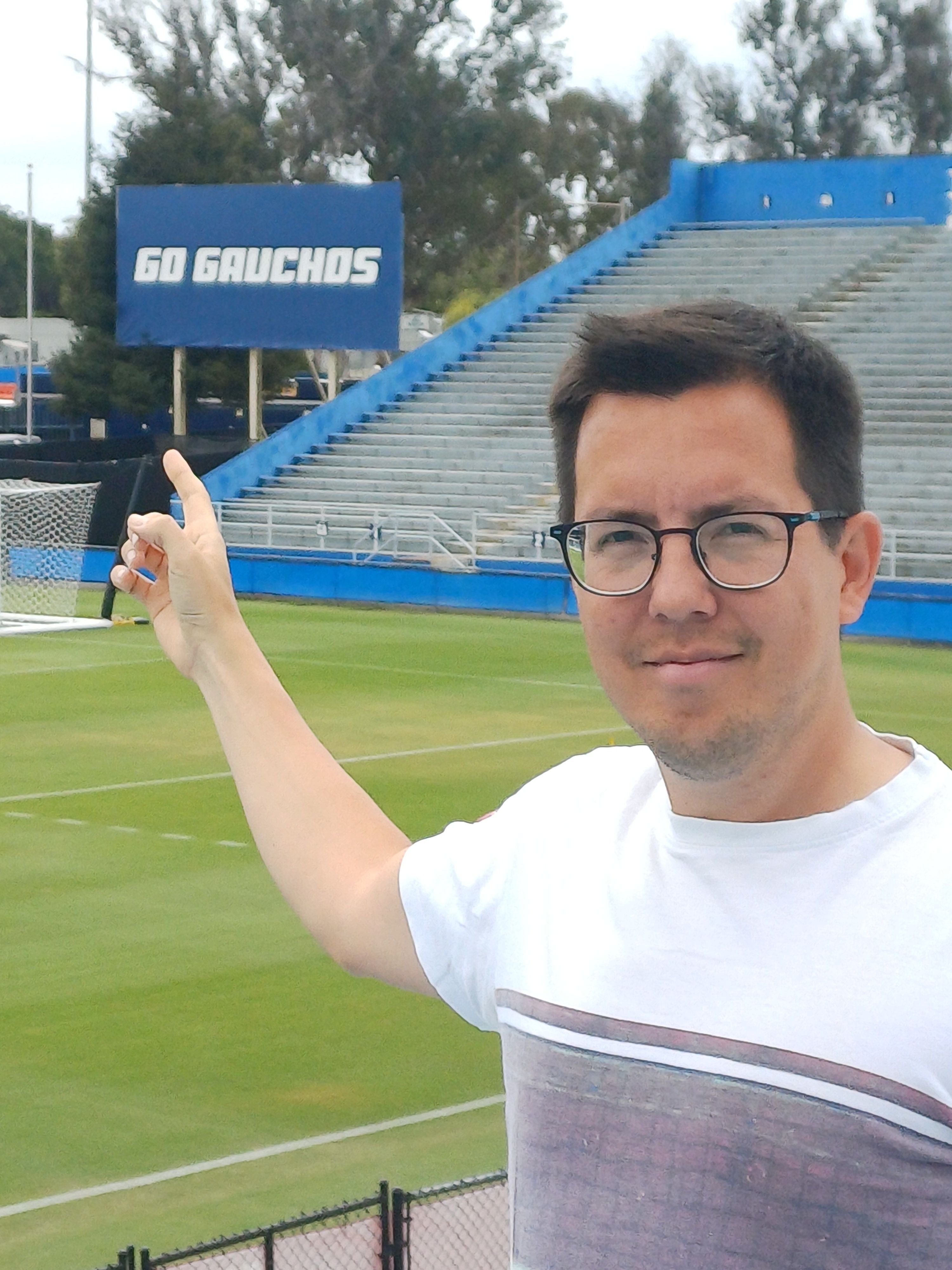 Ein Mann zeigt auf ein Schild mit der Aufschrift „Go Gauchos“ in einem leeren Stadion.