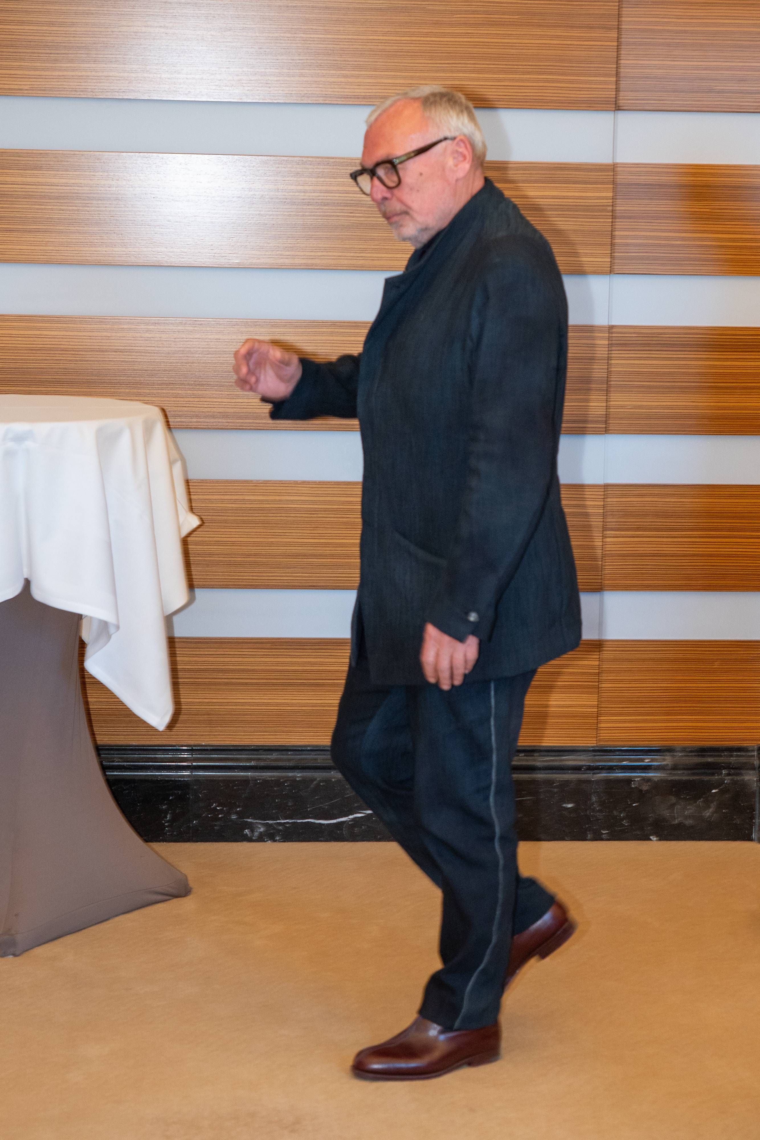 Ein Mann im Anzug geht an einem Stehtisch mit weißer Tischdecke vorbei.