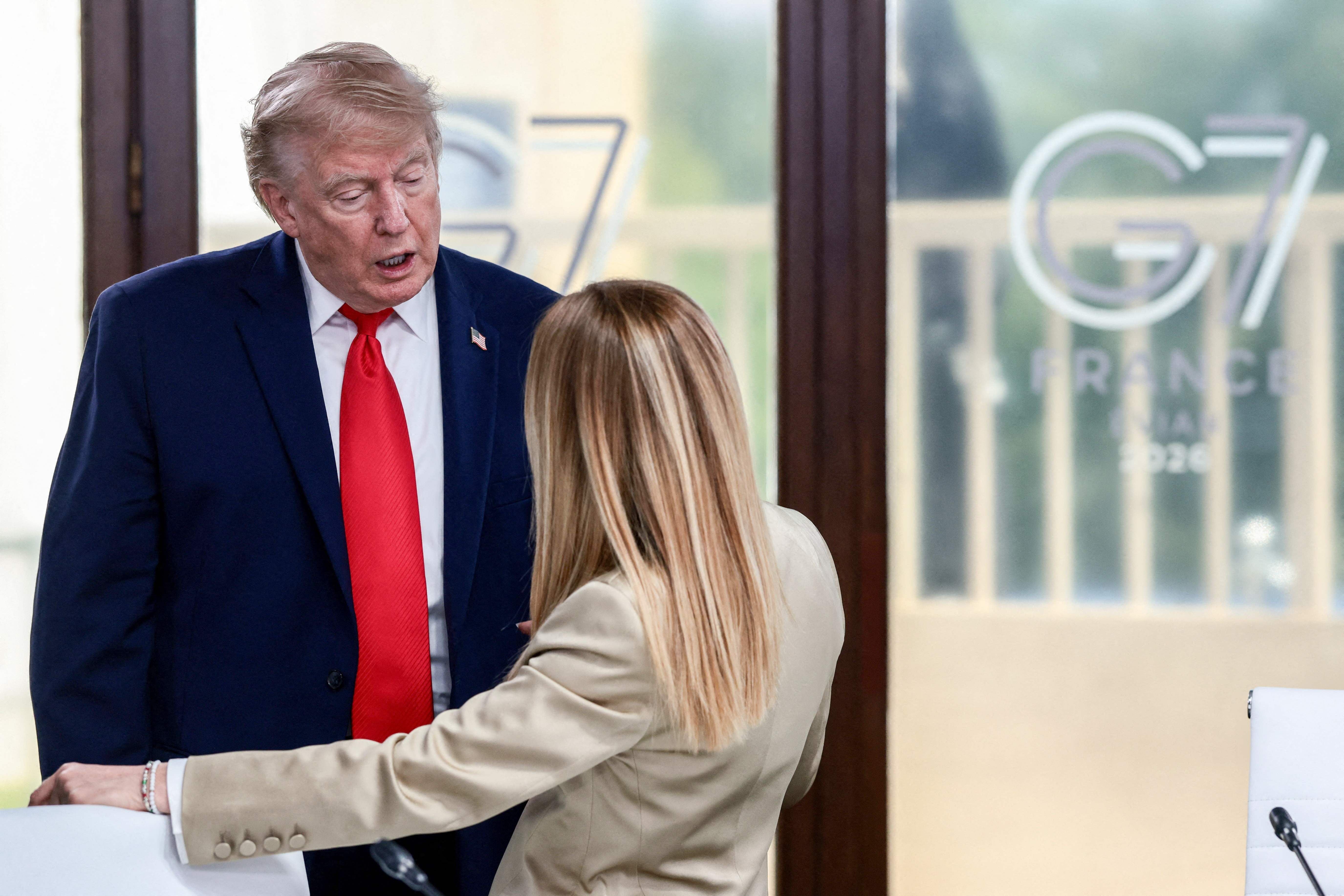 Zwei Personen unterhalten sich beim G7-Gipfel 2026 in einem Konferenzraum in Frankreich.