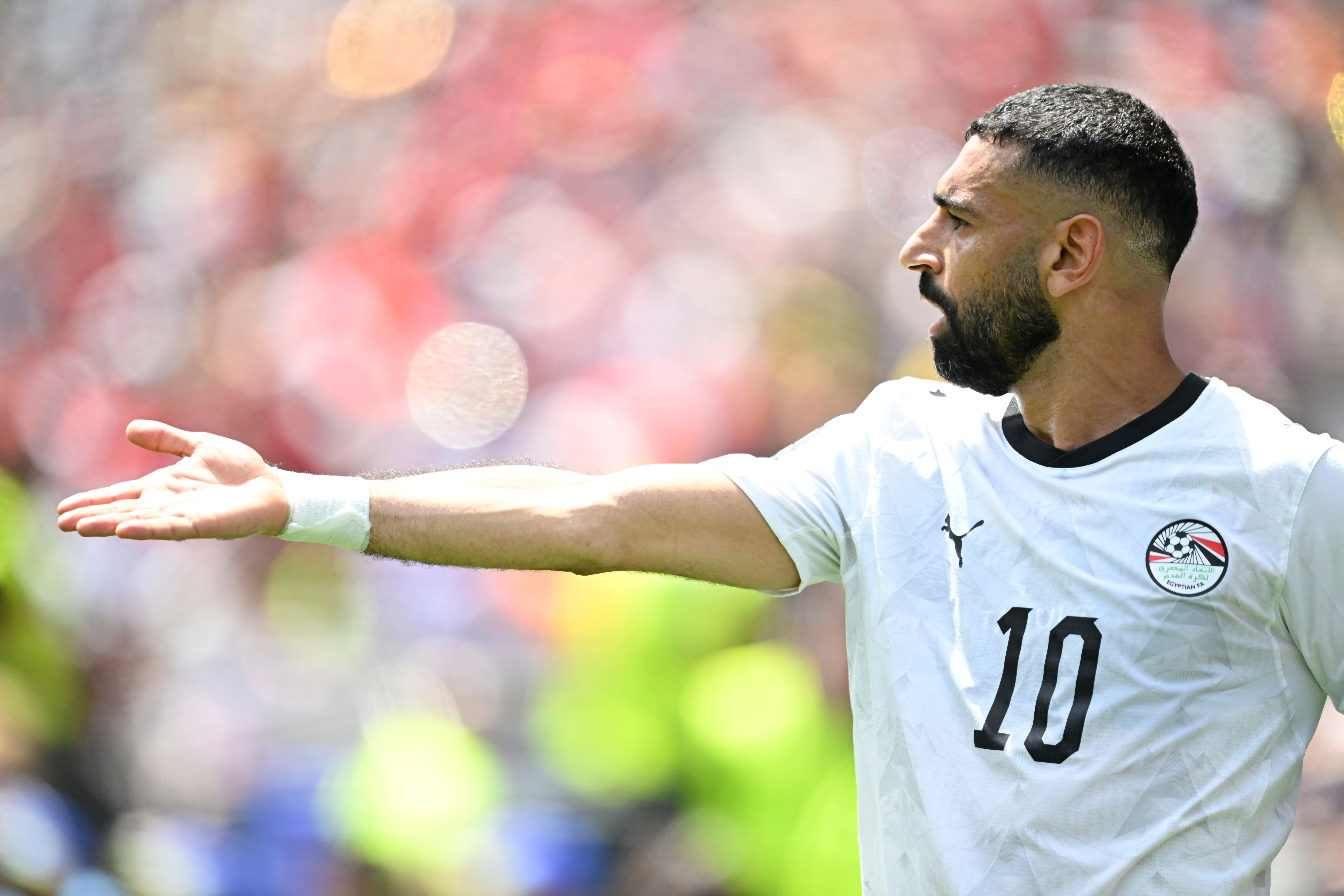 Fußballspieler im weißen Ägypten-Trikot mit ausgestrecktem Arm auf dem Spielfeld.
