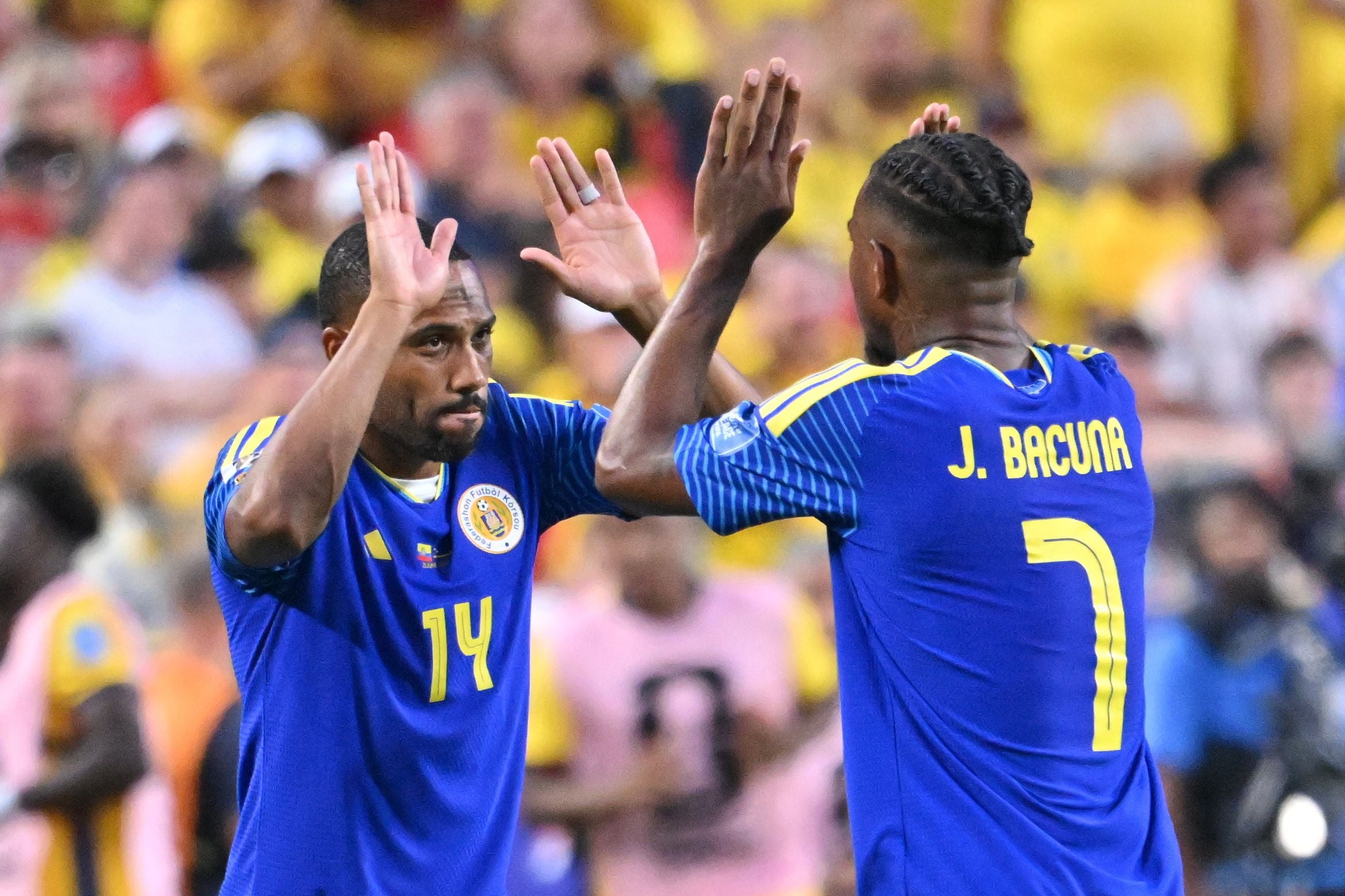 Zwei Fußballspieler aus Curaçao klatschen sich während eines Spiels ab.