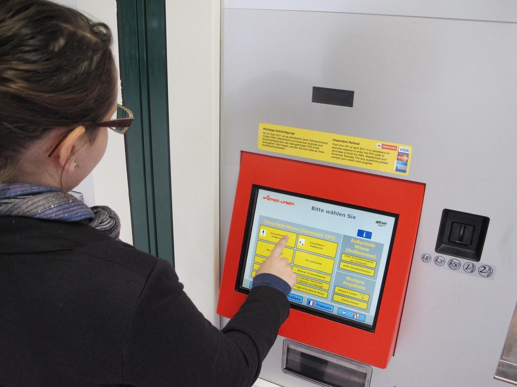 Frau tippt auf den Bildschirm eines Wiener Fahrkartenautomaten.