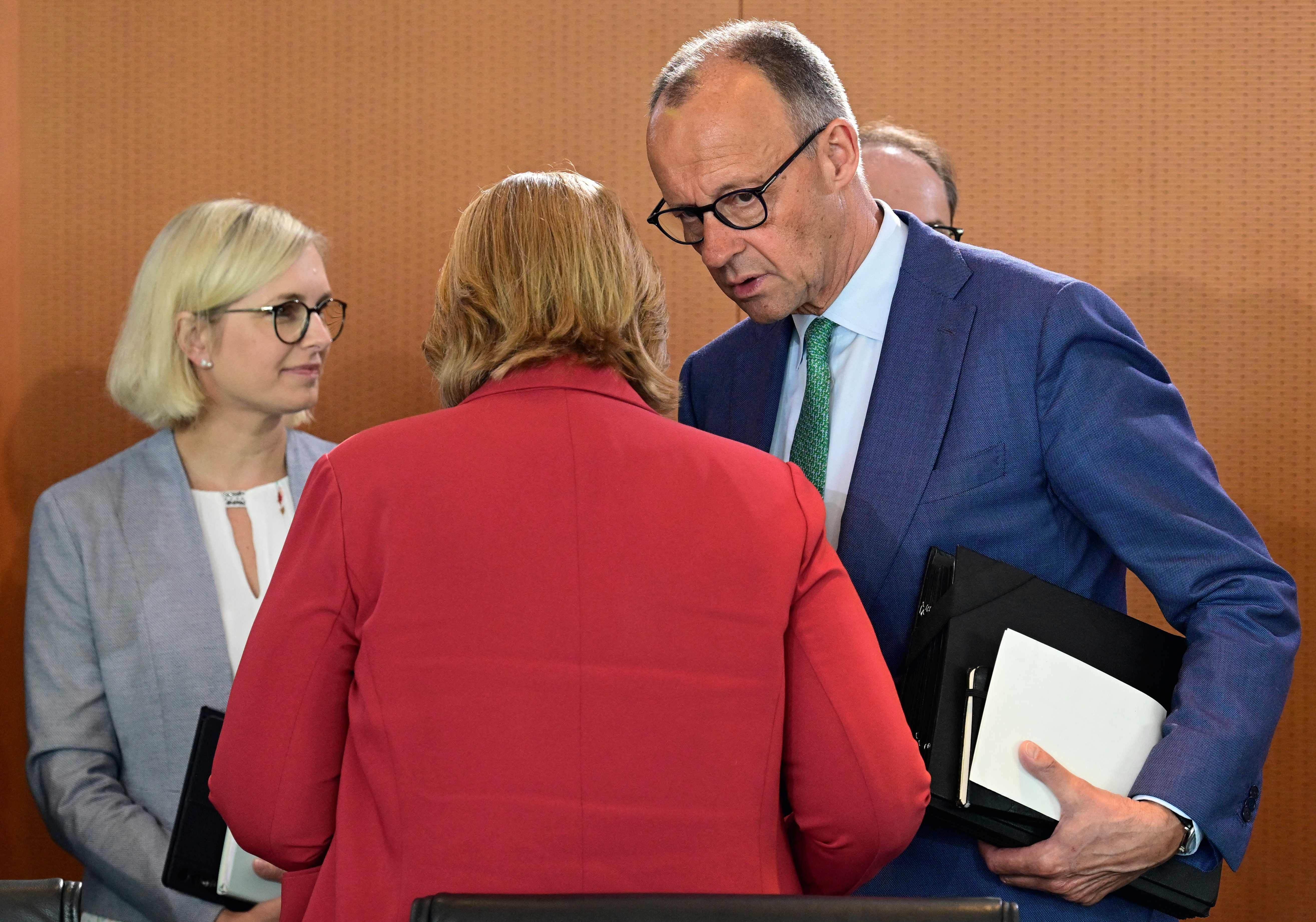 Drei Personen im Gespräch mit Aktenmappen bei einem Treffen in einem Konferenzraum.