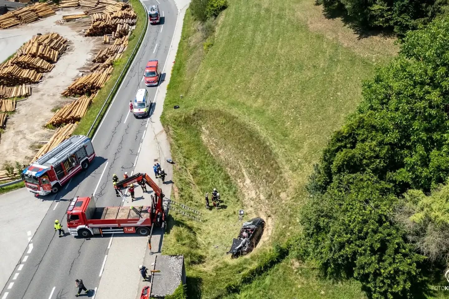 Unfallstelle mit Rettungskräften, zerstörtes Auto liegt neben der Straße im grünen Böschungsbereich.