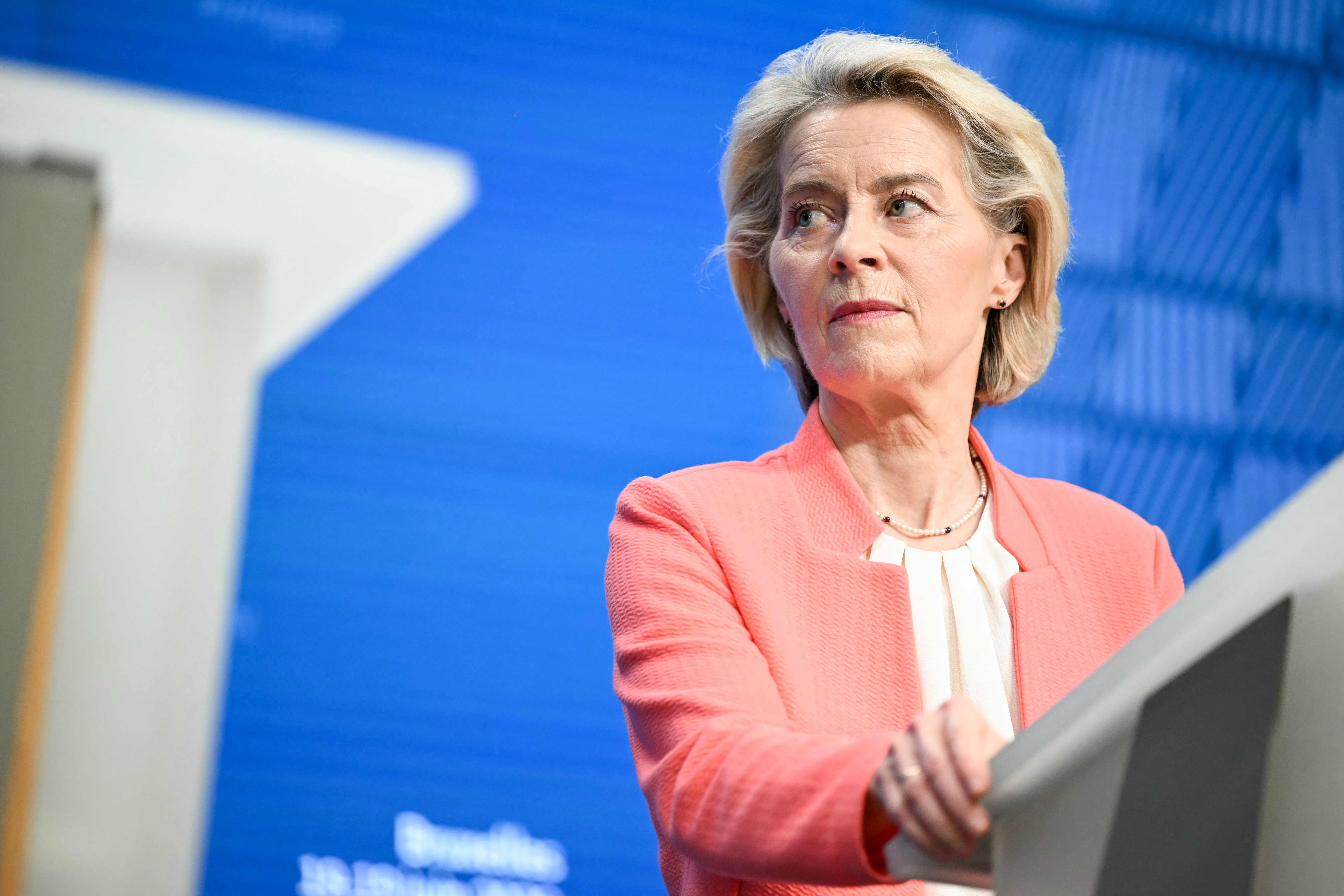 Frau am Rednerpult vor blauem Hintergrund, Gesicht unkenntlich gemacht.