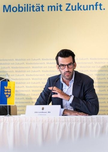 Ein Mann im Anzug spricht bei einer Pressekonferenz zum Thema Mobilität mit Zukunft.