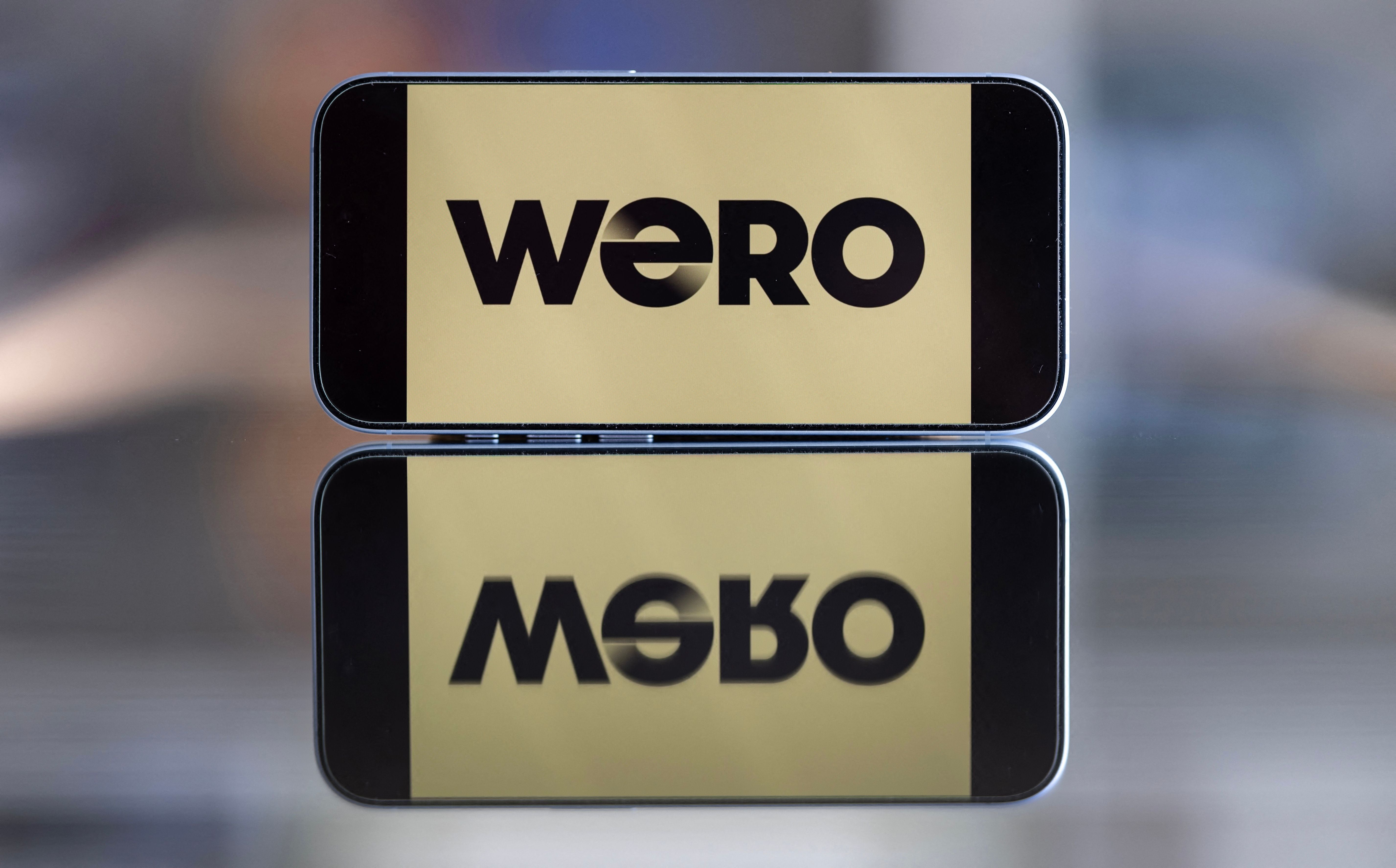 Ein Smartphone zeigt das Wero-Logo mit Spiegelung auf einer glänzenden Oberfläche.