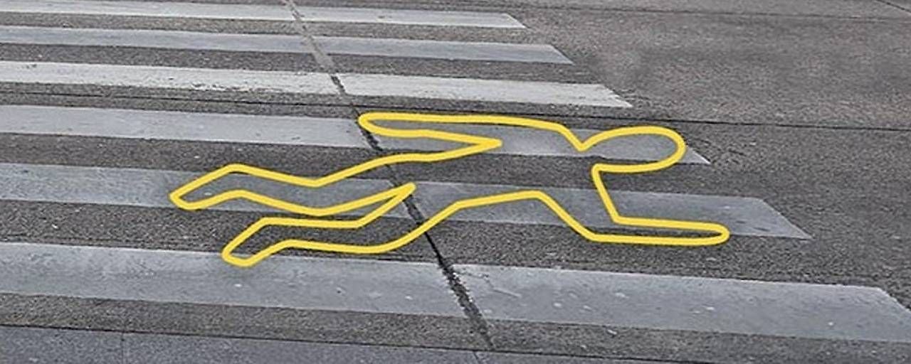 Gelbe Umrisszeichnung einer liegenden Person auf einem Zebrastreifen als Warnhinweis.