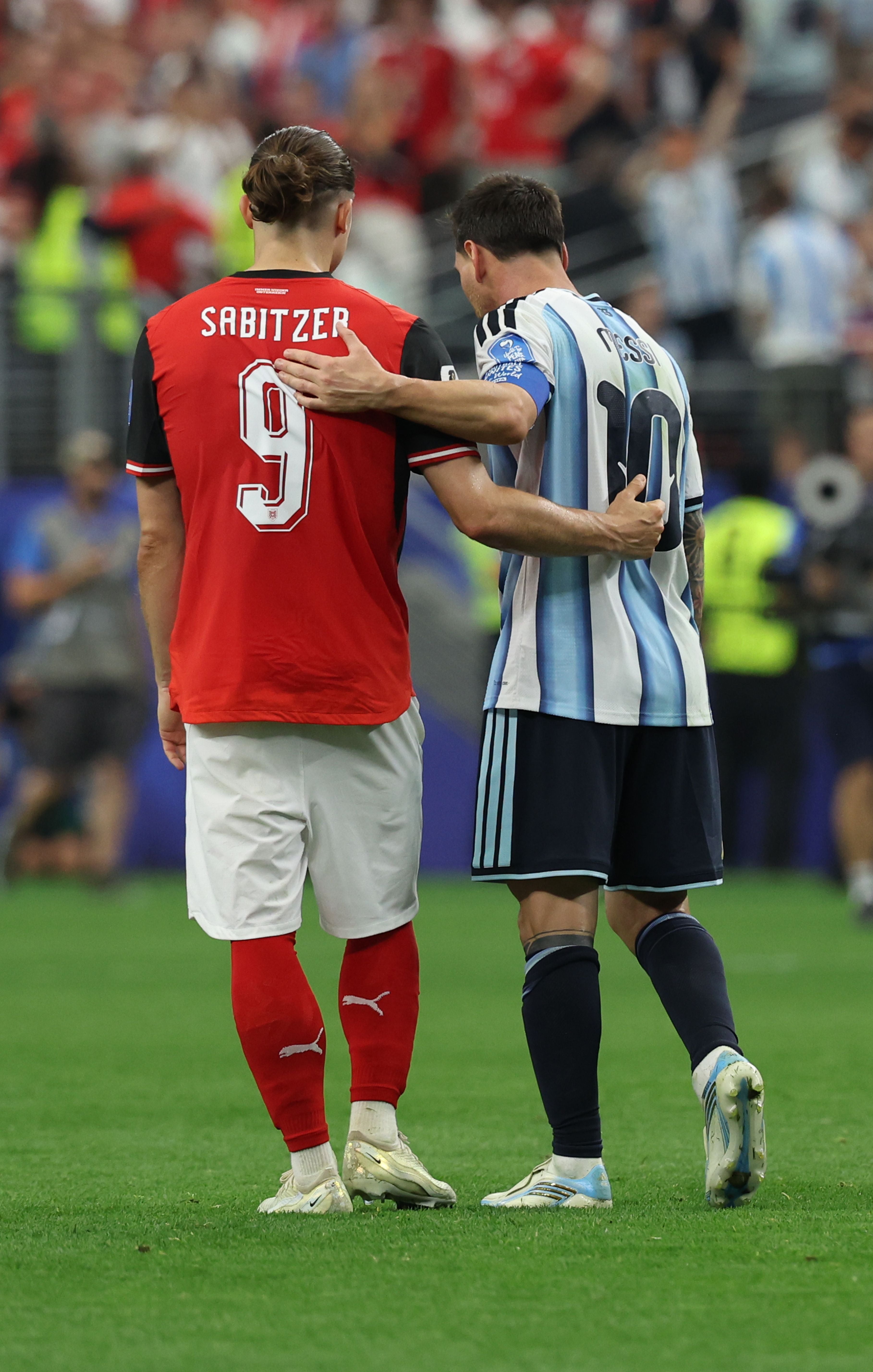 Zwei Fußballspieler, Sabitzer und Messi, umarmen sich nach dem Spiel auf dem Spielfeld.