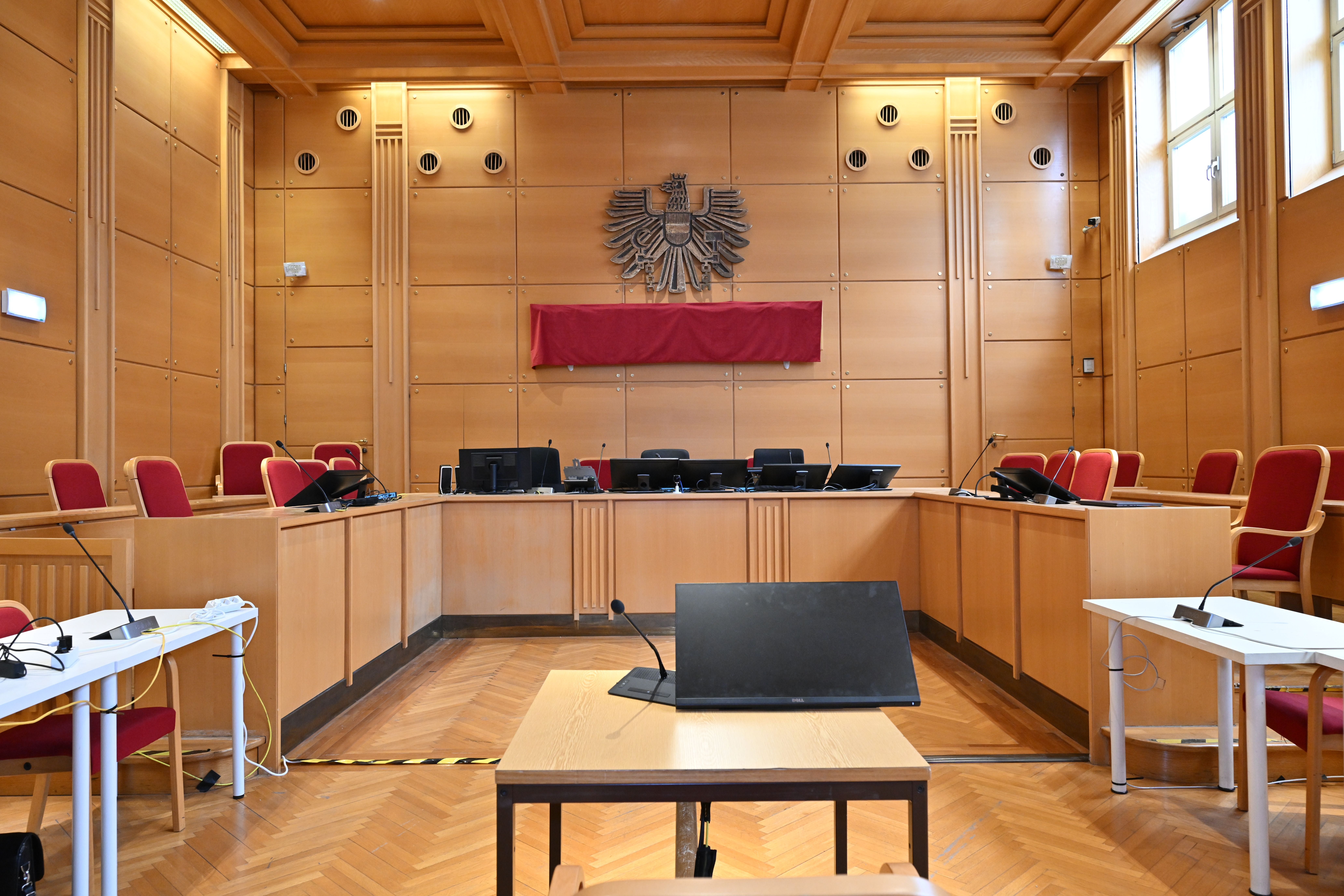 Leerer Gerichtssaal mit Holzwänden und roten Stühlen im Landesgericht Linz.