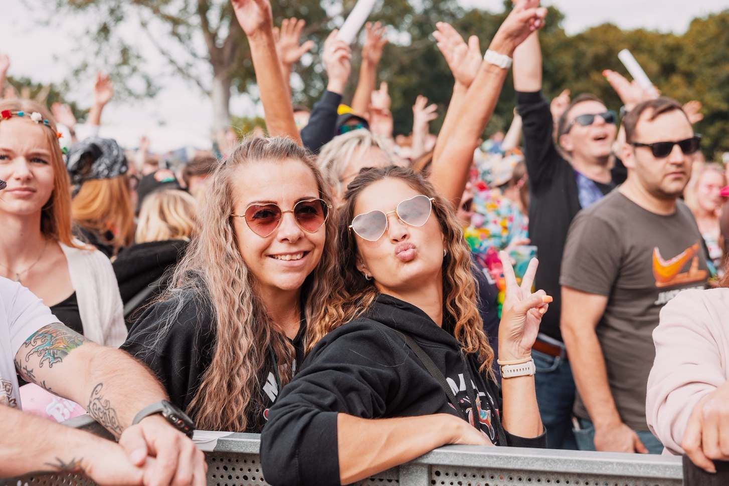 Menschen stehen dicht gedrängt auf einem Open-Air-Konzert, einige zeigen das Peace-Zeichen.