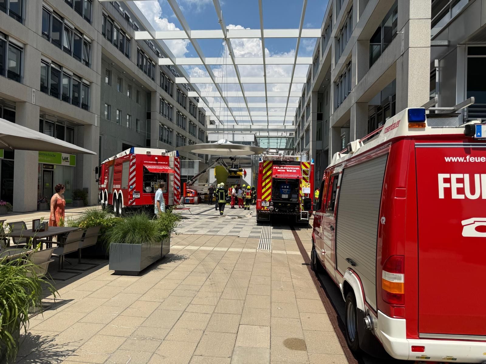 Mehrere Feuerwehrfahrzeuge und ein Rettungshubschrauber vor einem modernen Bürogebäude.
