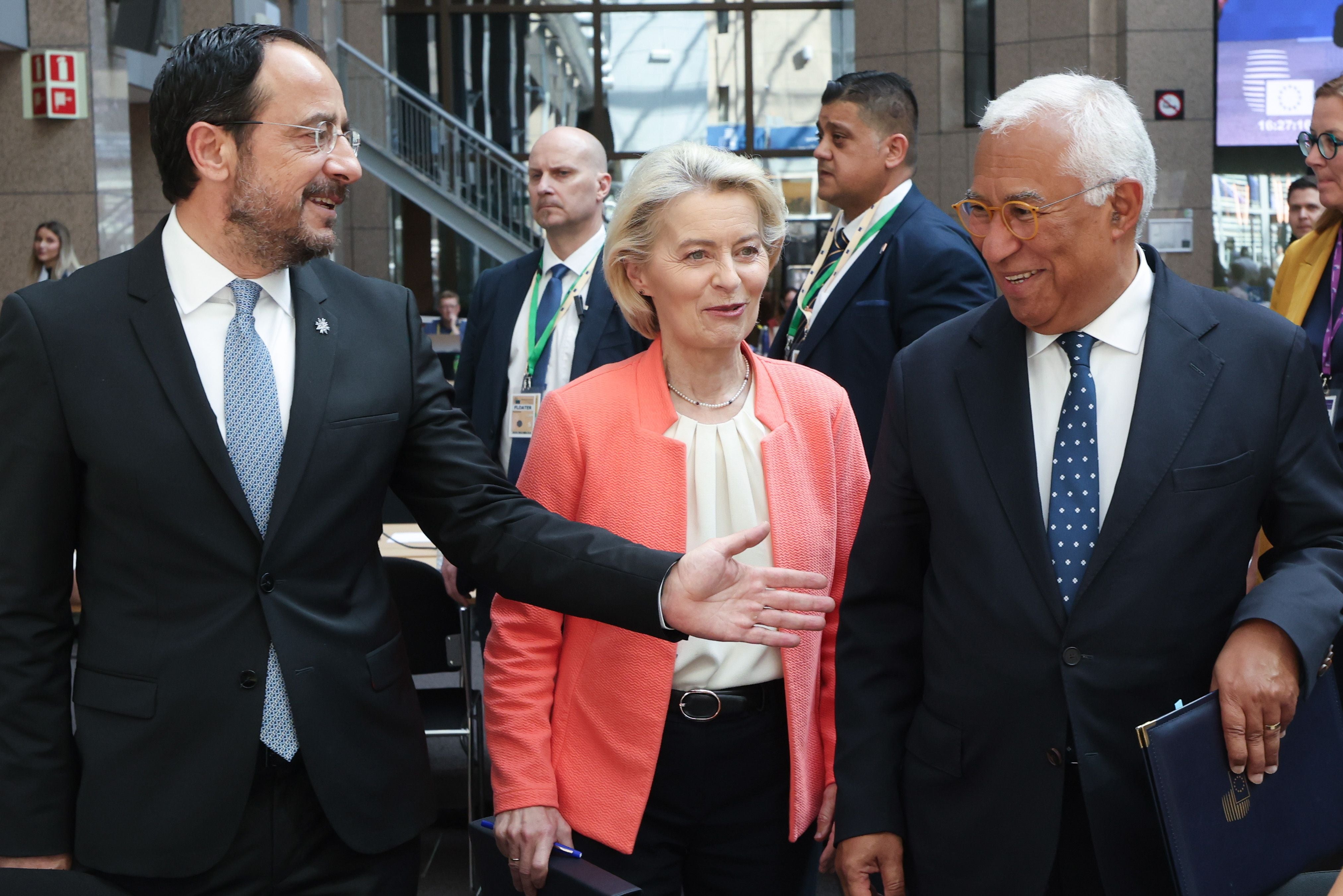 Mehrere Personen im Anzug unterhalten sich auf einem EU-Gipfeltreffen in einem Konferenzgebäude.