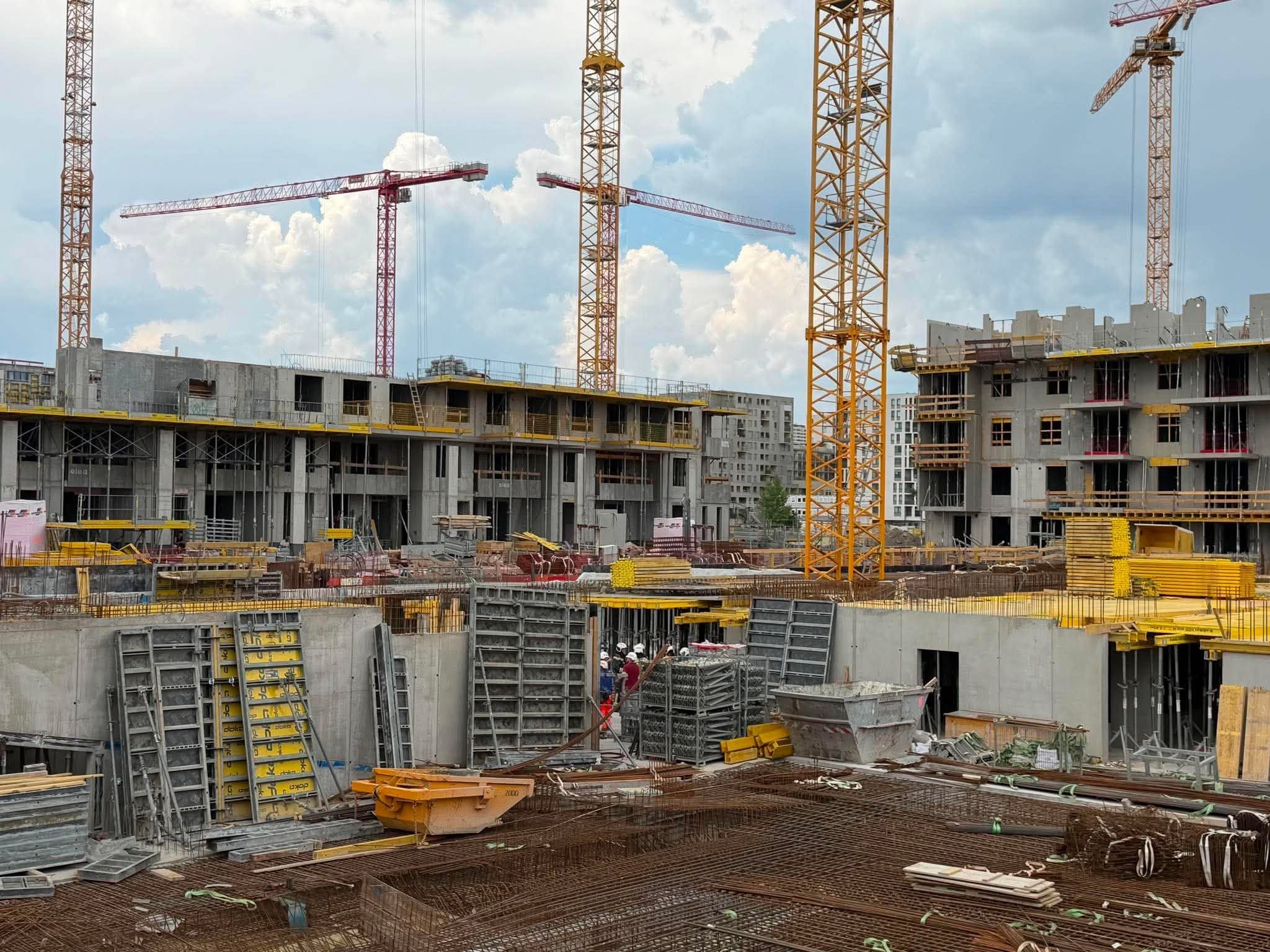 Baustelle eines Wohnbauprojekts mit Kränen, Baumaterialien und Rohbauten in Liesing.
