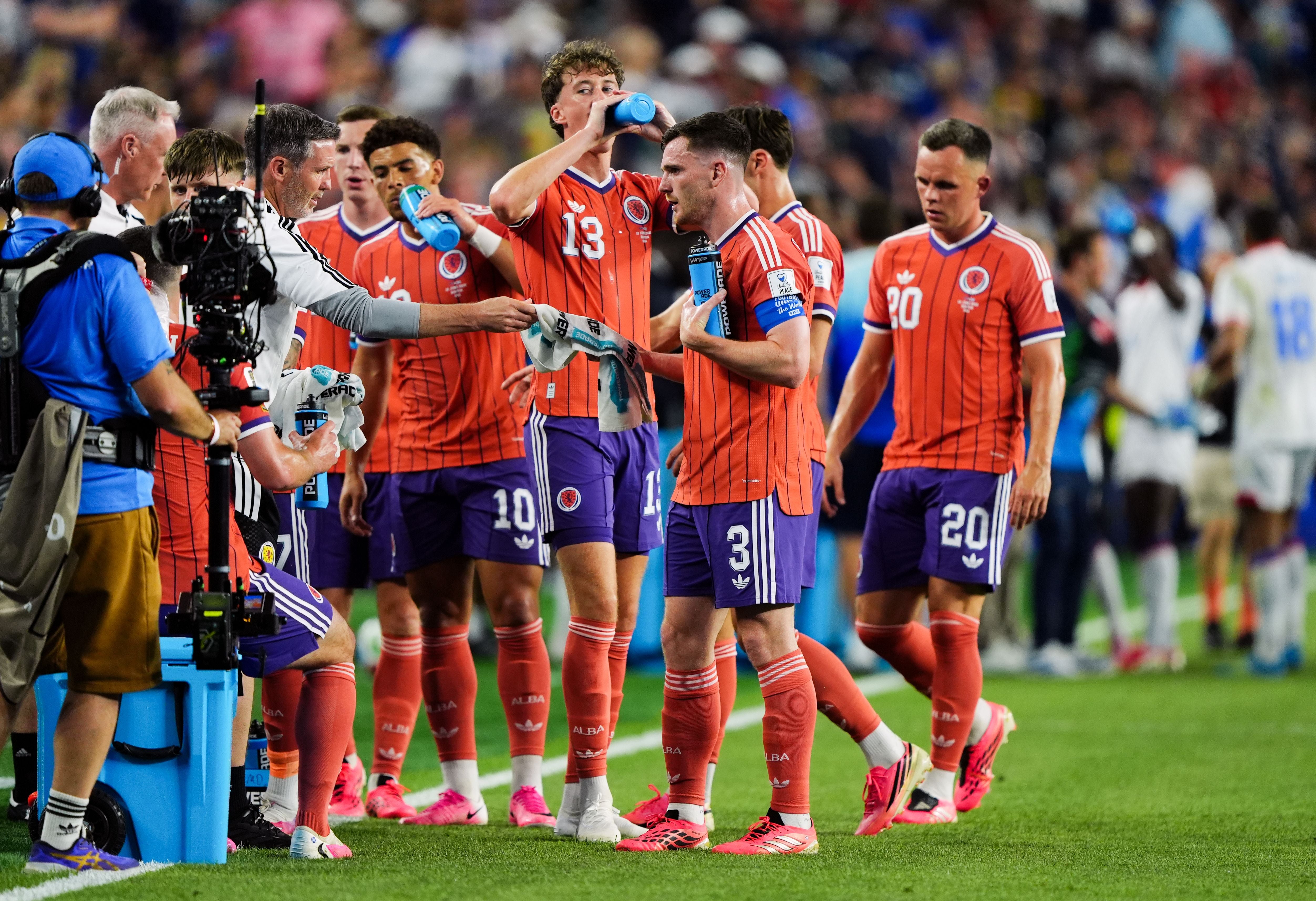 Schottische Fußballspieler machen während eines Spiels eine Trinkpause am Spielfeldrand.