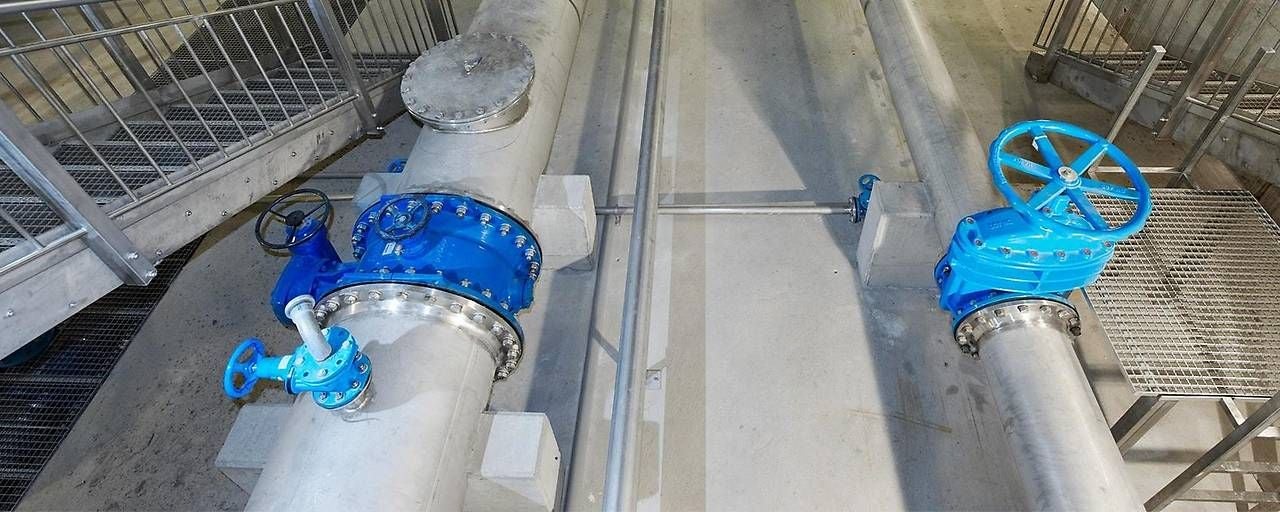 Zwei große Rohre mit blauen Absperrventilen in einer Industrieanlage.